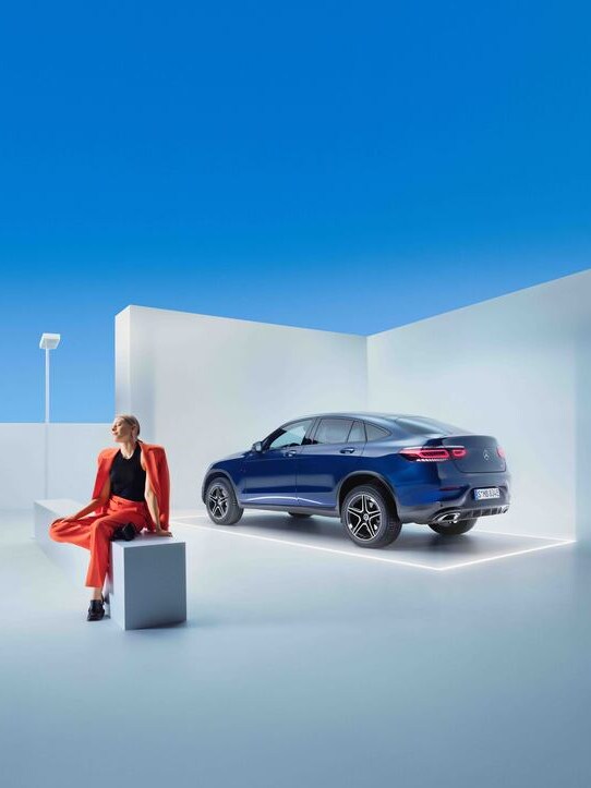 Donna seduta su una panchina con sullo sfondo una GLC Coupé