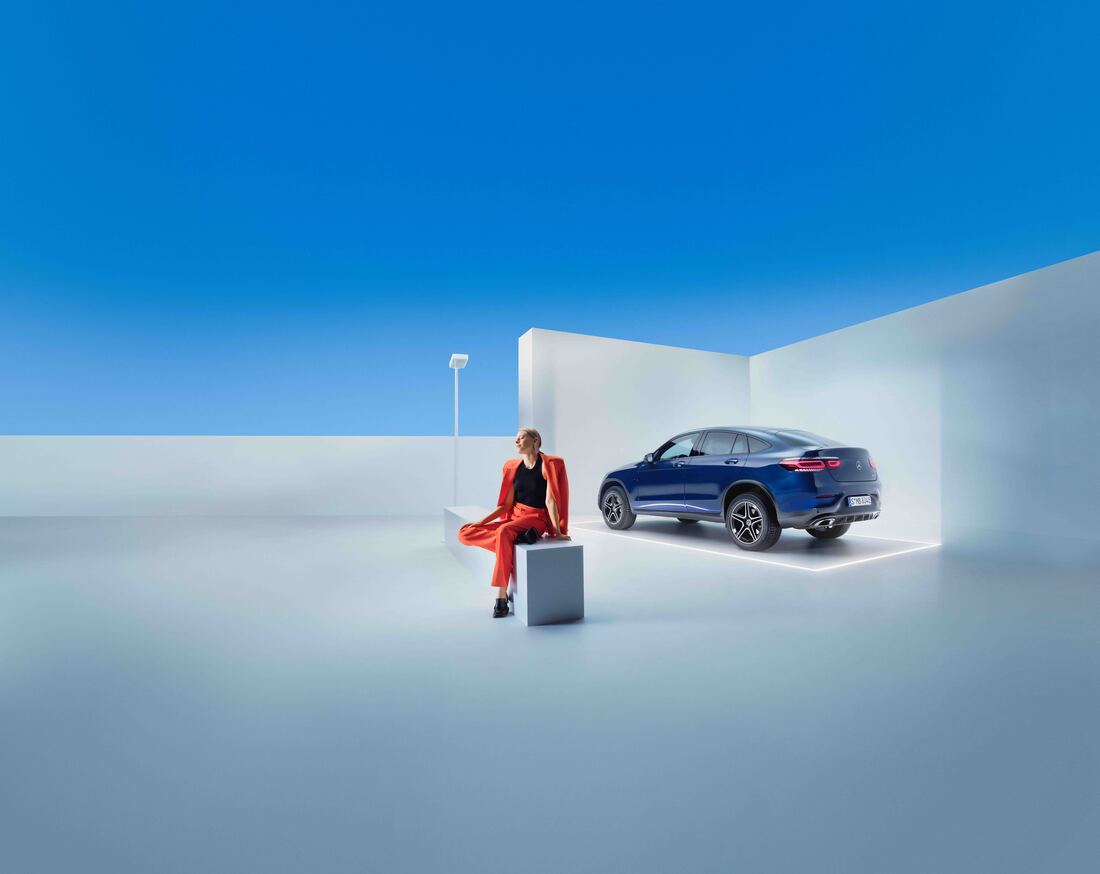 Service Contracts | Mercedes-Benz Donna seduta su una panchina con sullo sfondo una GLC Coupé