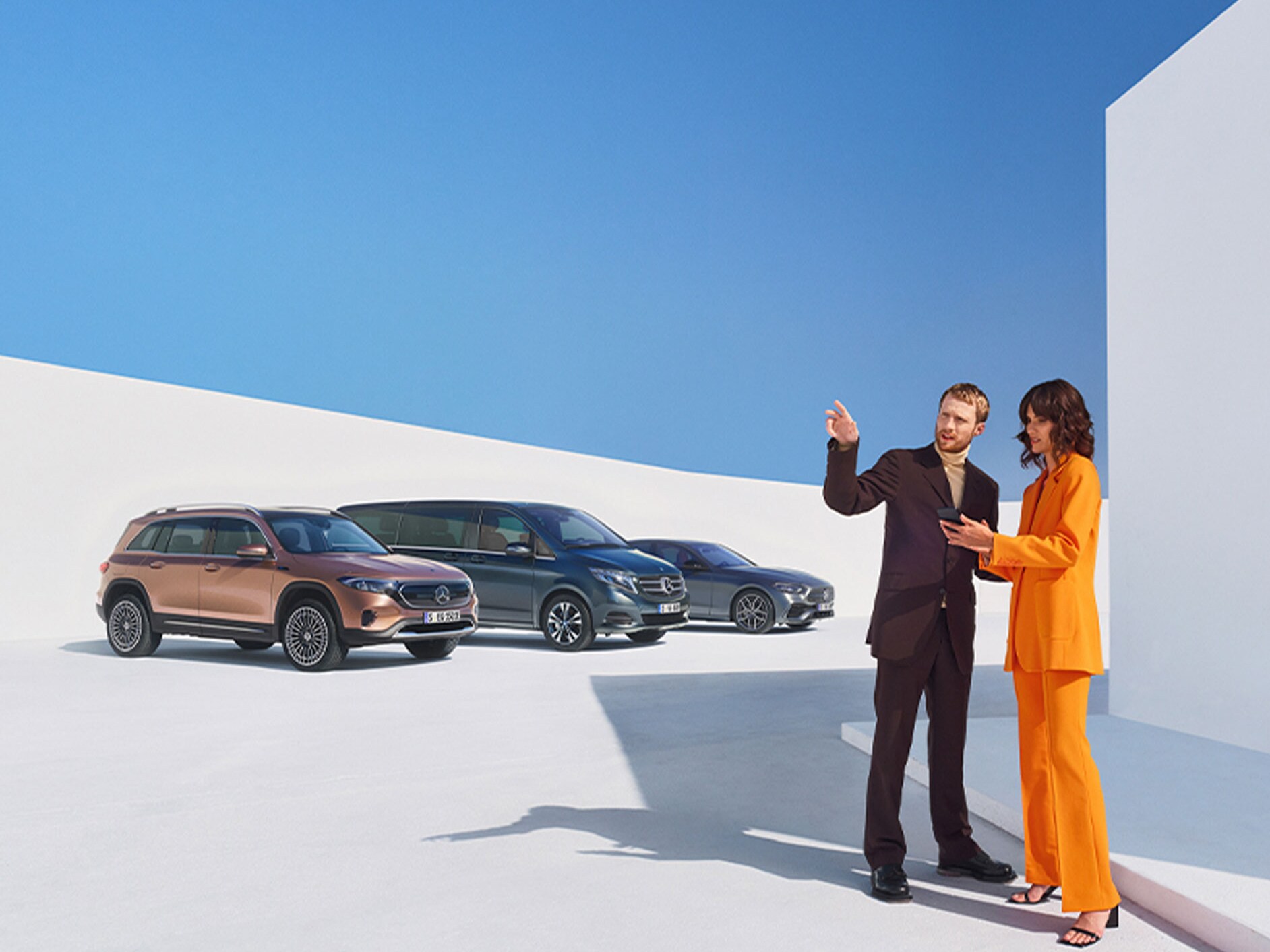 Un uomo e una donna davanti ad alcuni veicoli Mercedes-Benz.