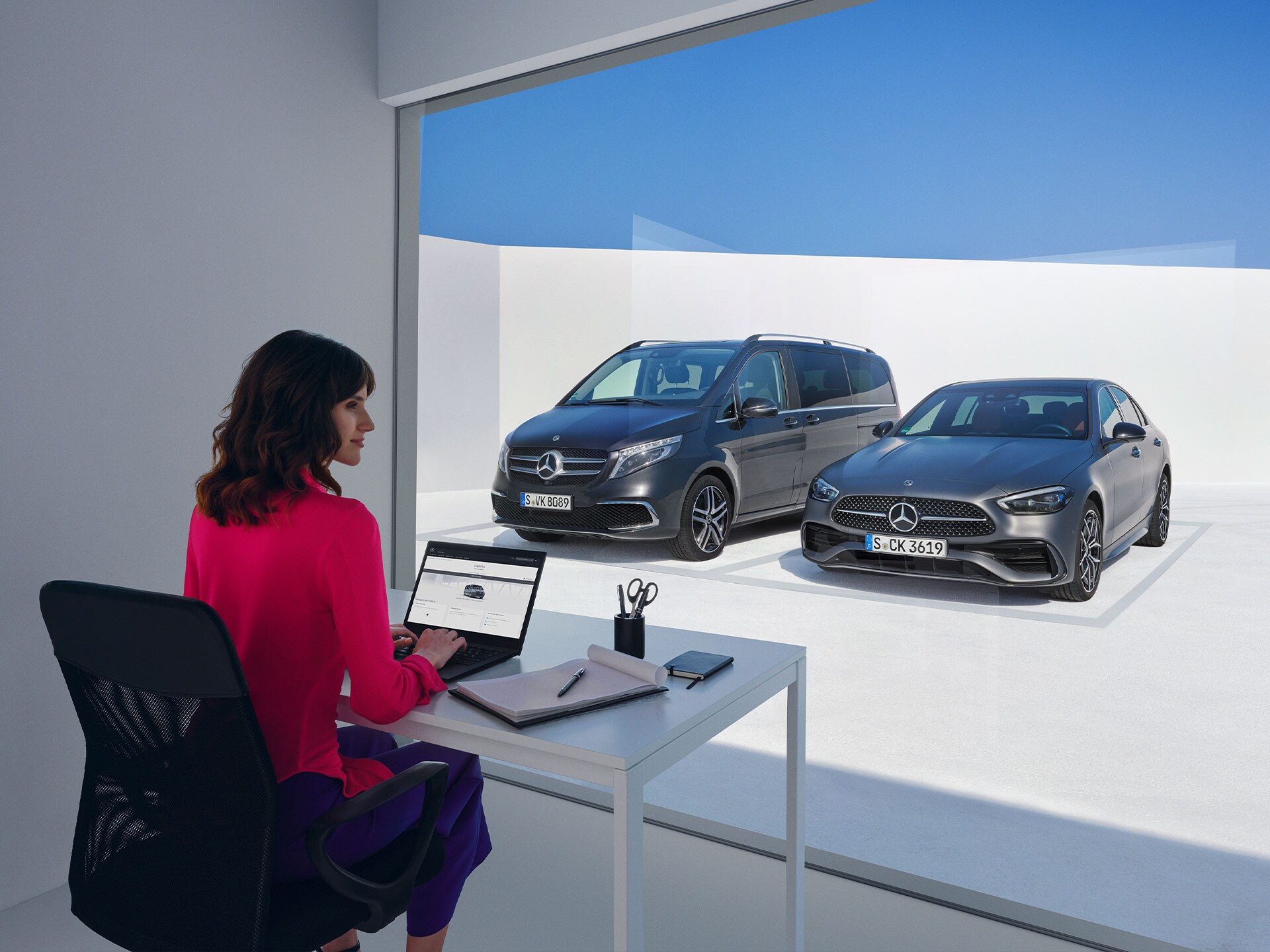 Donne sedute davanti alla Mercedes-Benz Classe V e Classe C mentre guardano un computer portatile.