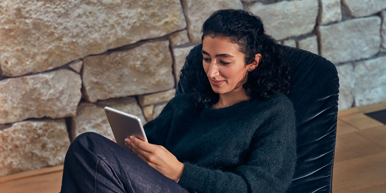 Rimani connesso con la tecnologia moderna Una persona mentre si rilassa con un tablet su una sedia di fronte a un muro di pietra