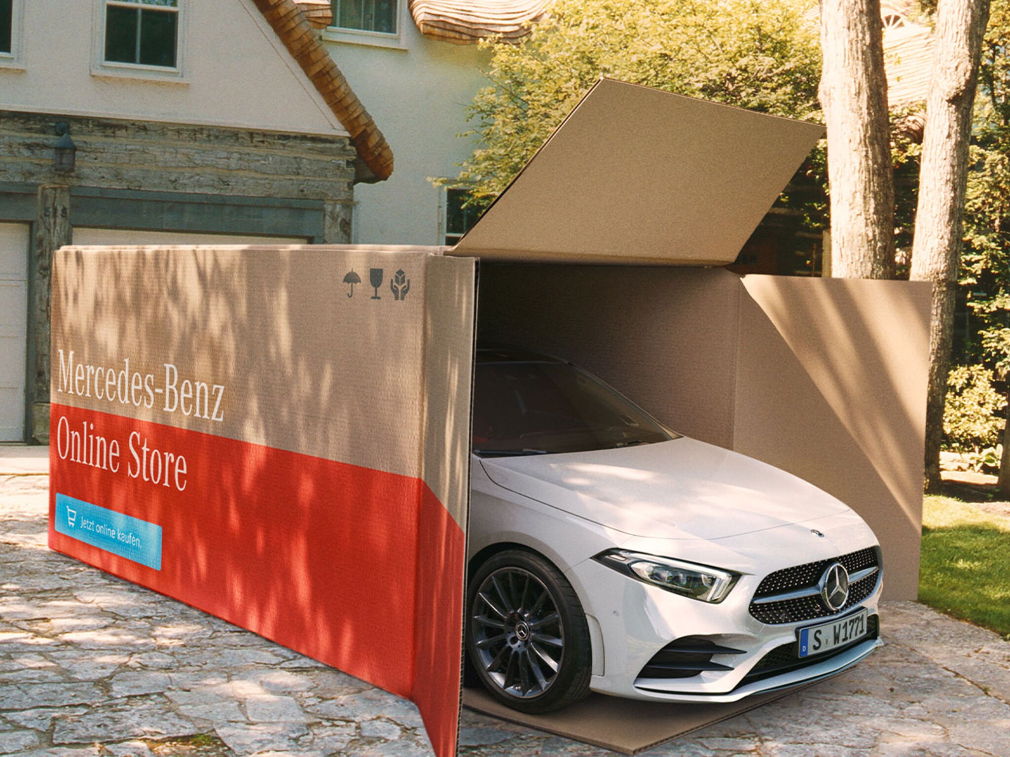 Un veicolo Mercedes-Benz parzialmente scoperto in una grande scatola di cartone con la scritta "Mercedes-Benz Online Store"