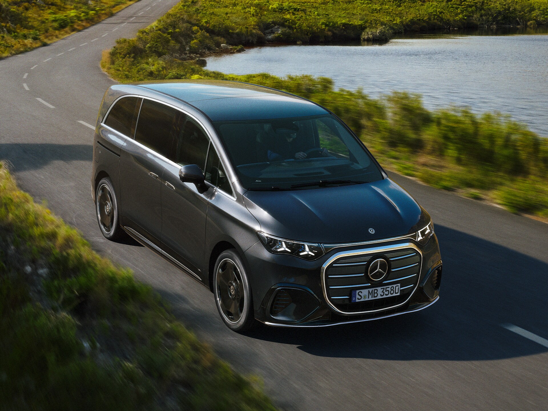 La Mercedes-Benz VLE su una strada battuta dal vento accanto a un lago.