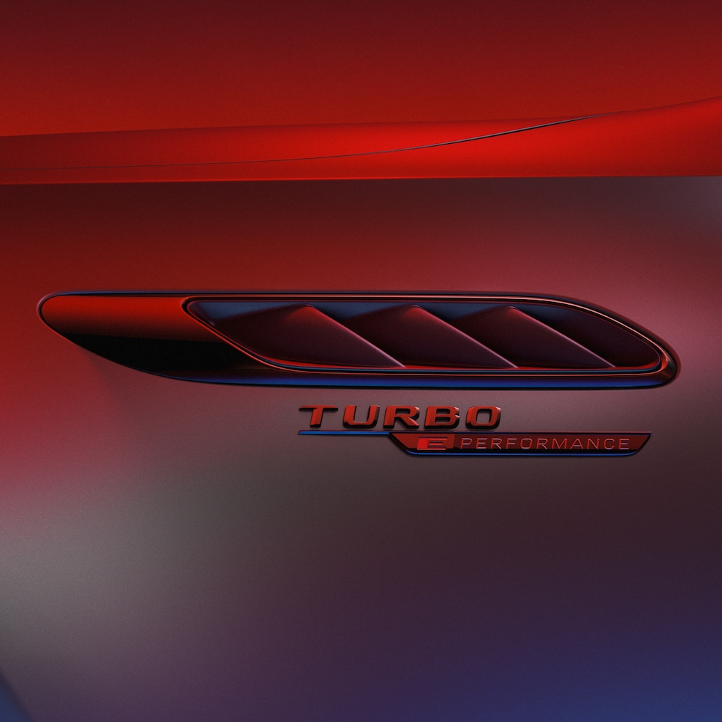 Targhetta TURBO E PERFORMANCE sui parafanghi anteriori, illuminata da una luce rossa.