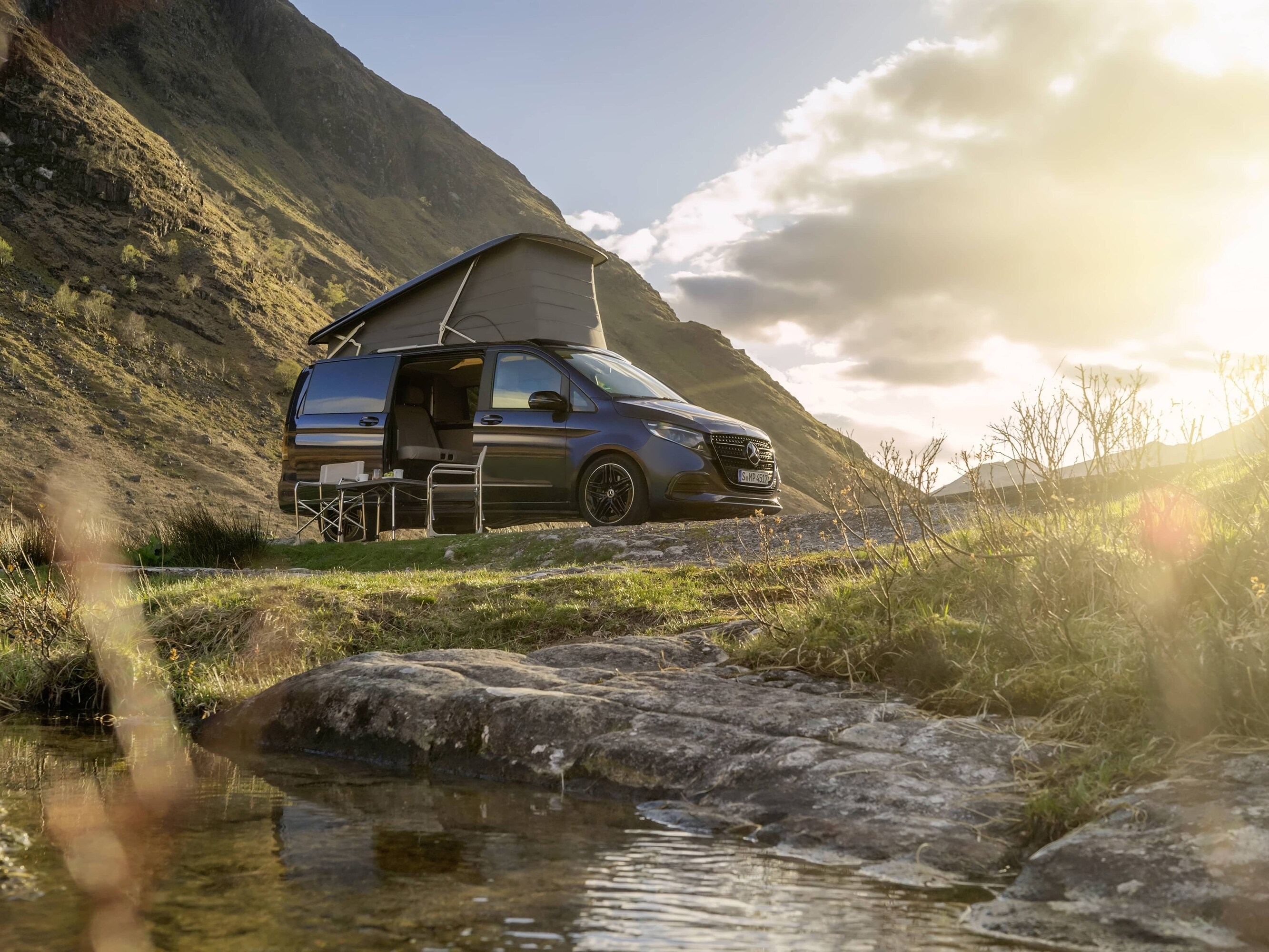 Un camper Mercedes-Benz Marco Polo con tetto a soffietto, immerso in un suggestivo paesaggio montano, che mette in risalto l’avventura all’aria aperta e la libertà della “vanlife”.