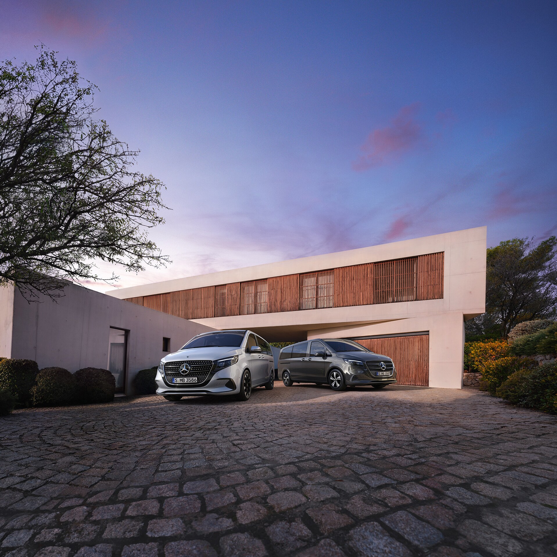 Una Mercedes-Benz Classe V davanti a una prestigiosa villa moderna al tramonto.
