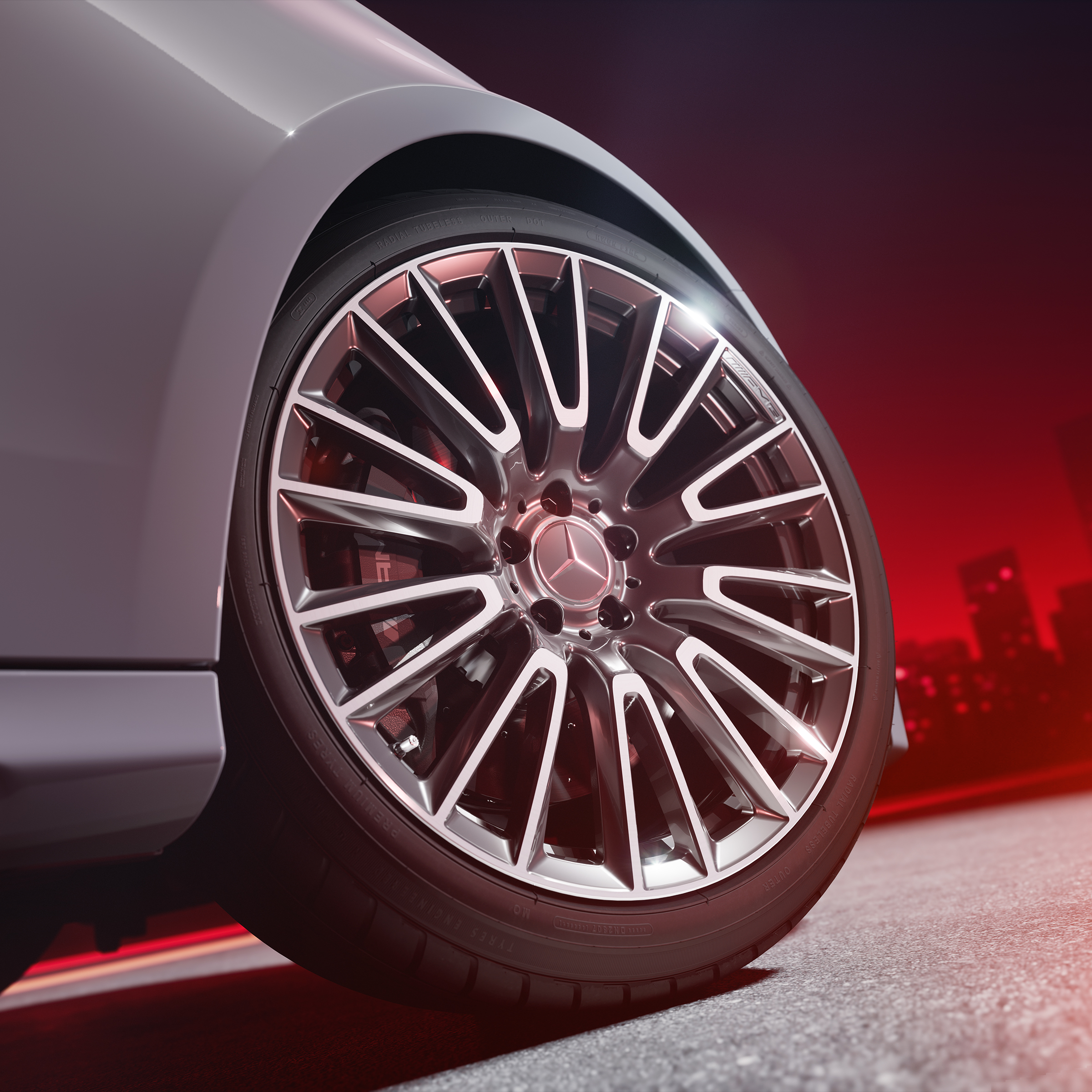 Primo piano di un cerchio fucinato AMG con sistema frenante ad alte prestazioni in materiale composito AMG e pinze freni verniciate in rosso.