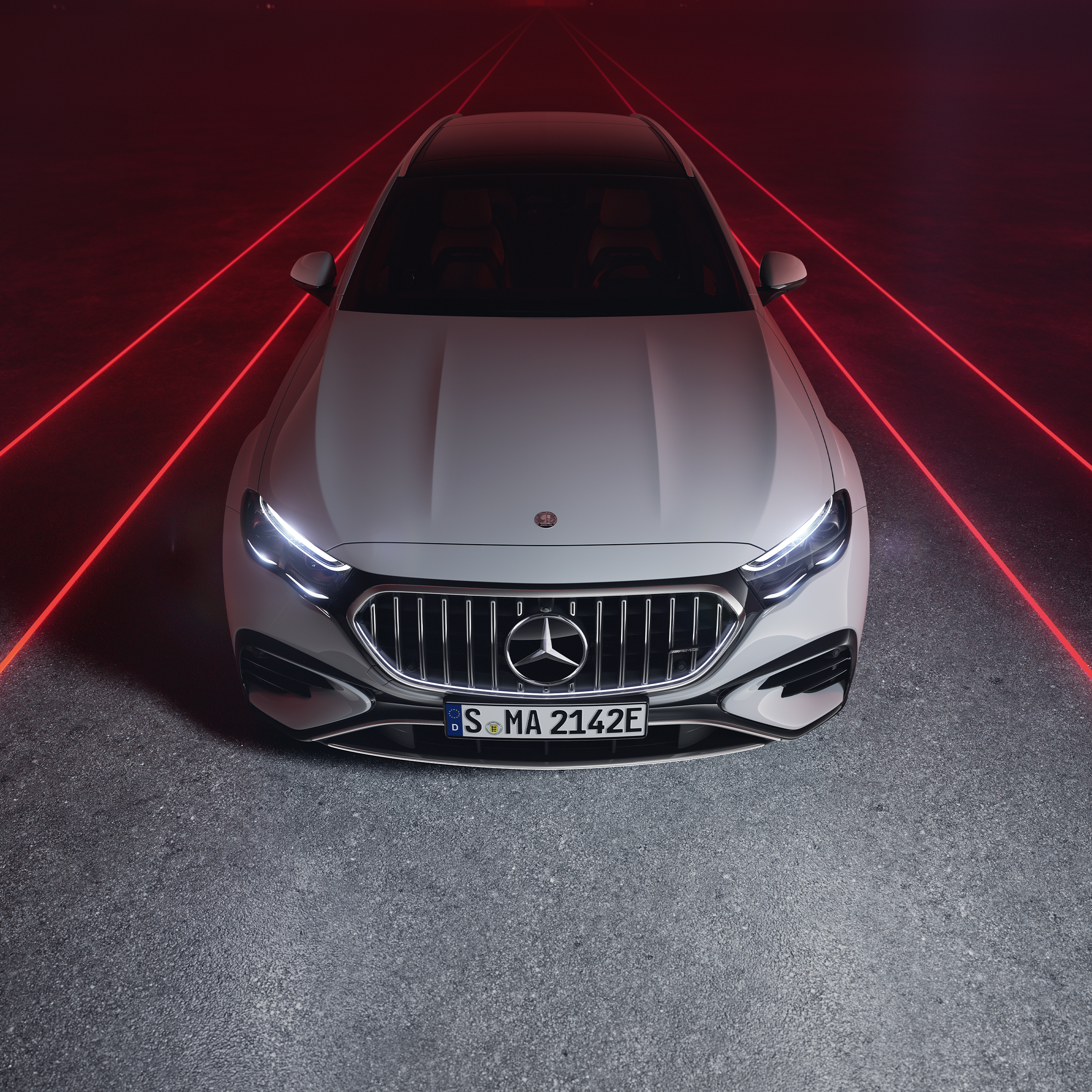 Vista frontale della Mercedes-AMG E 53 HYBRID 4MATIC+ con sfondo rosso, vista dall'alto.