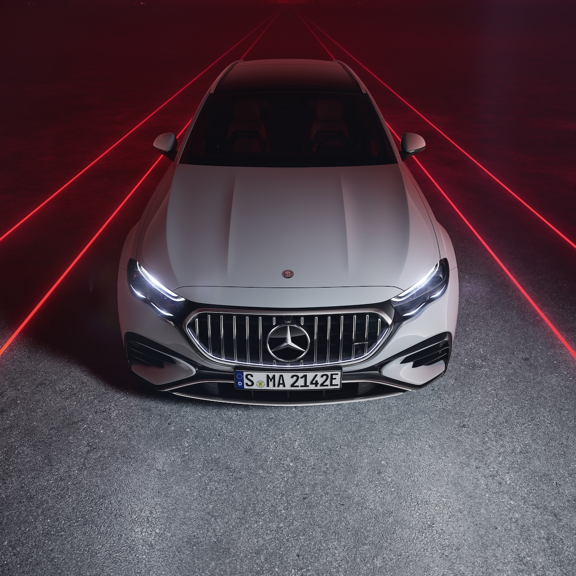 Vista frontale della Mercedes-AMG E 53 HYBRID 4MATIC+ con sfondo rosso, vista dall'alto.