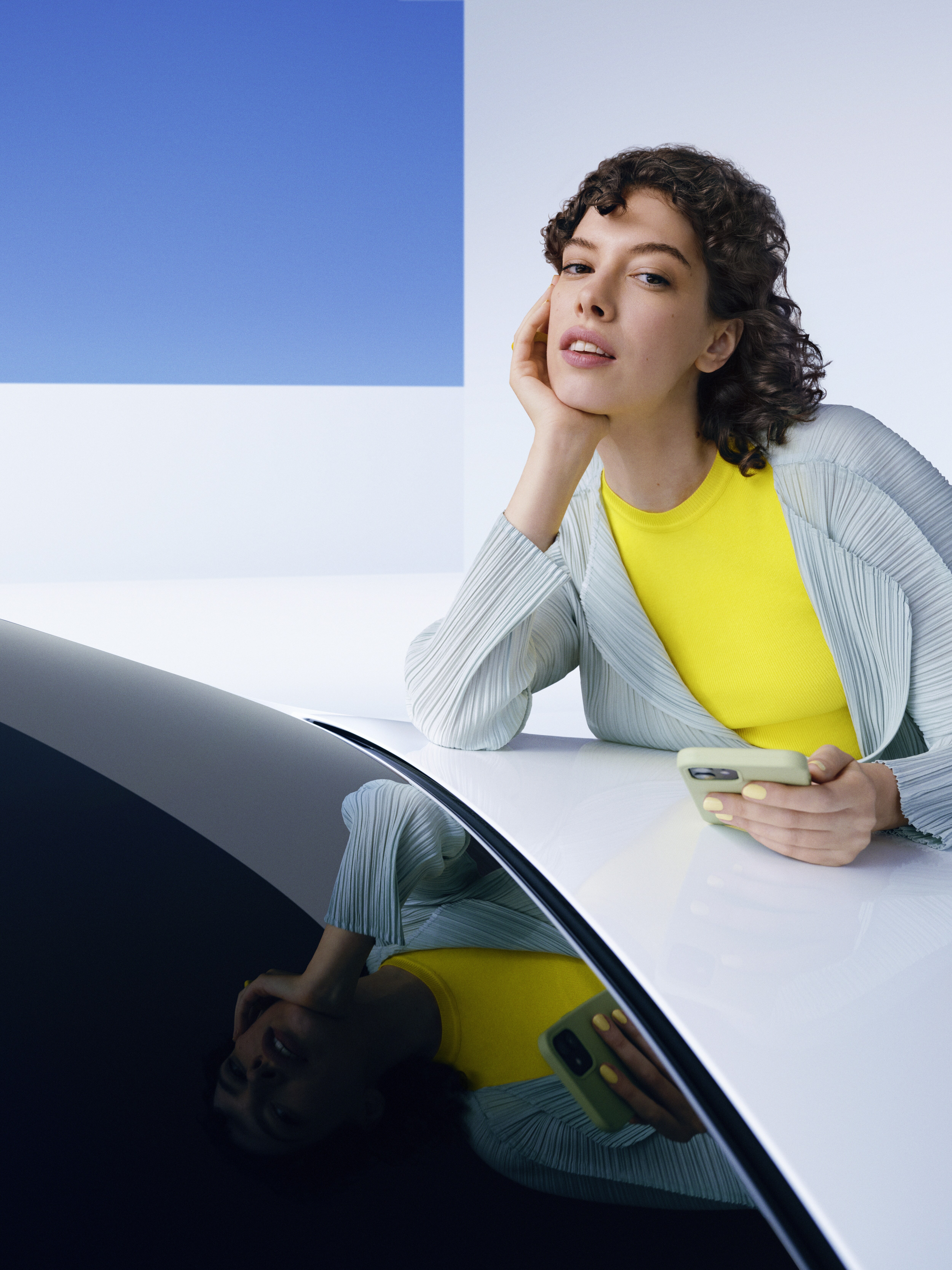 Donna con uno smartphone poggiata sul cofano di una Mercedes-Benz