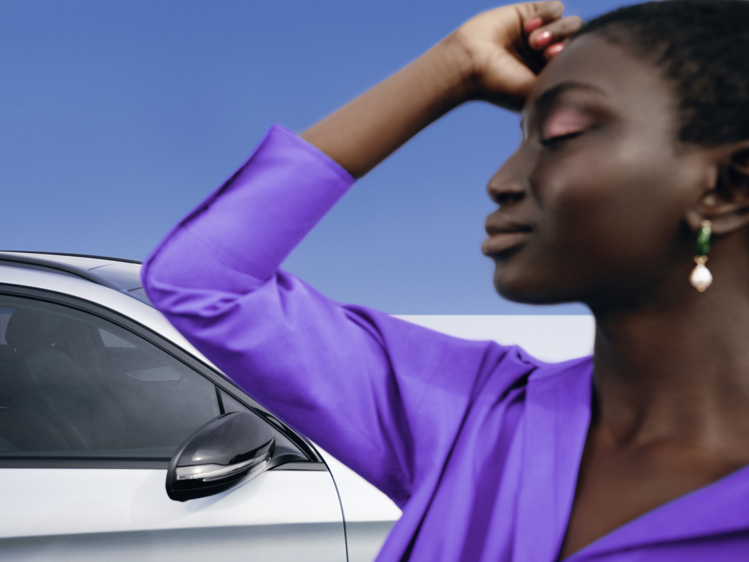 Mercedes-Benz | Prodotti originali per la pulizia Una donna in piedi, rilassata davanti alla sua Mercedes con un’espressione appagata sul volto.