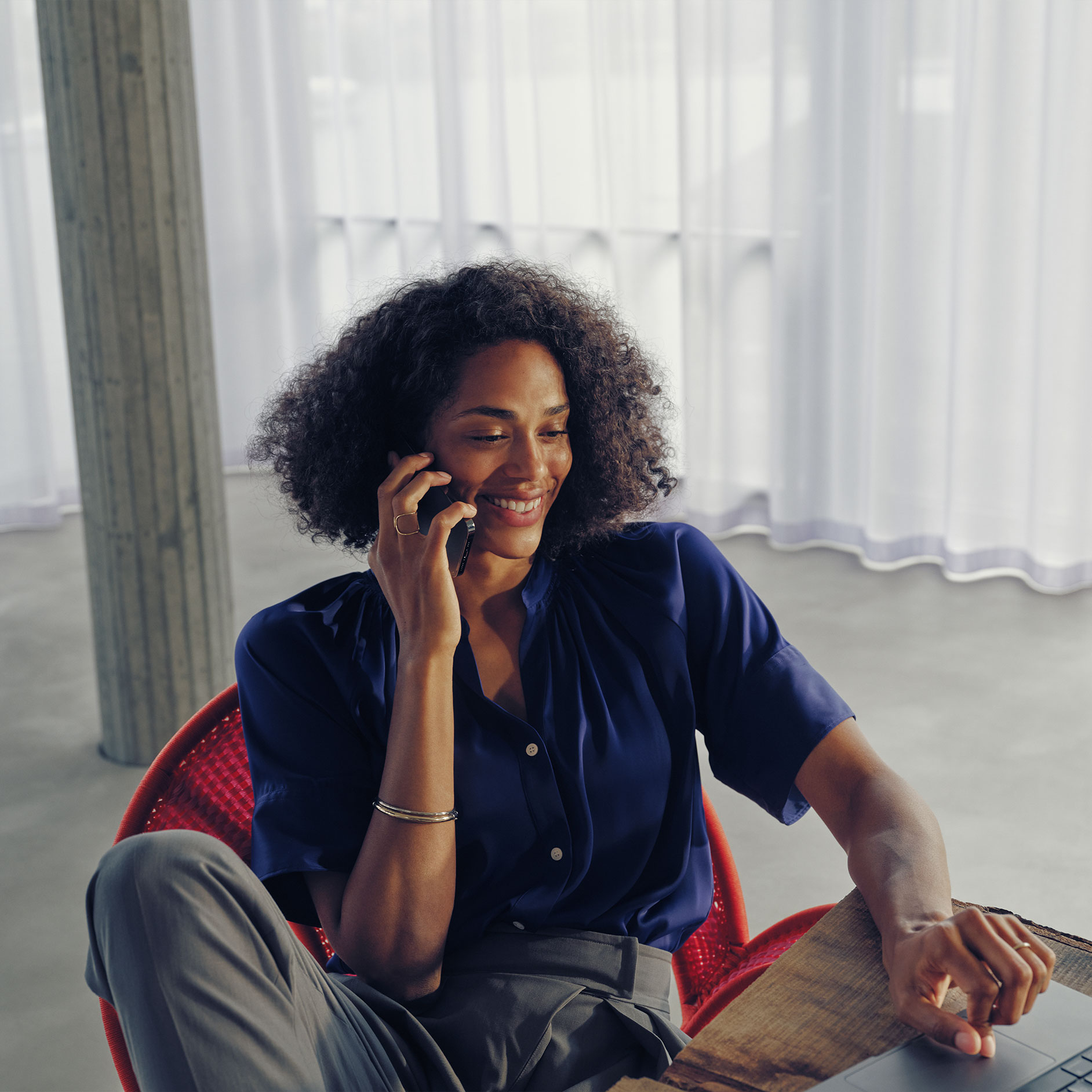 Domande | Ricarica | Mercedes-Benz Una donna seduta a un tavolo mentre parla al telefono.