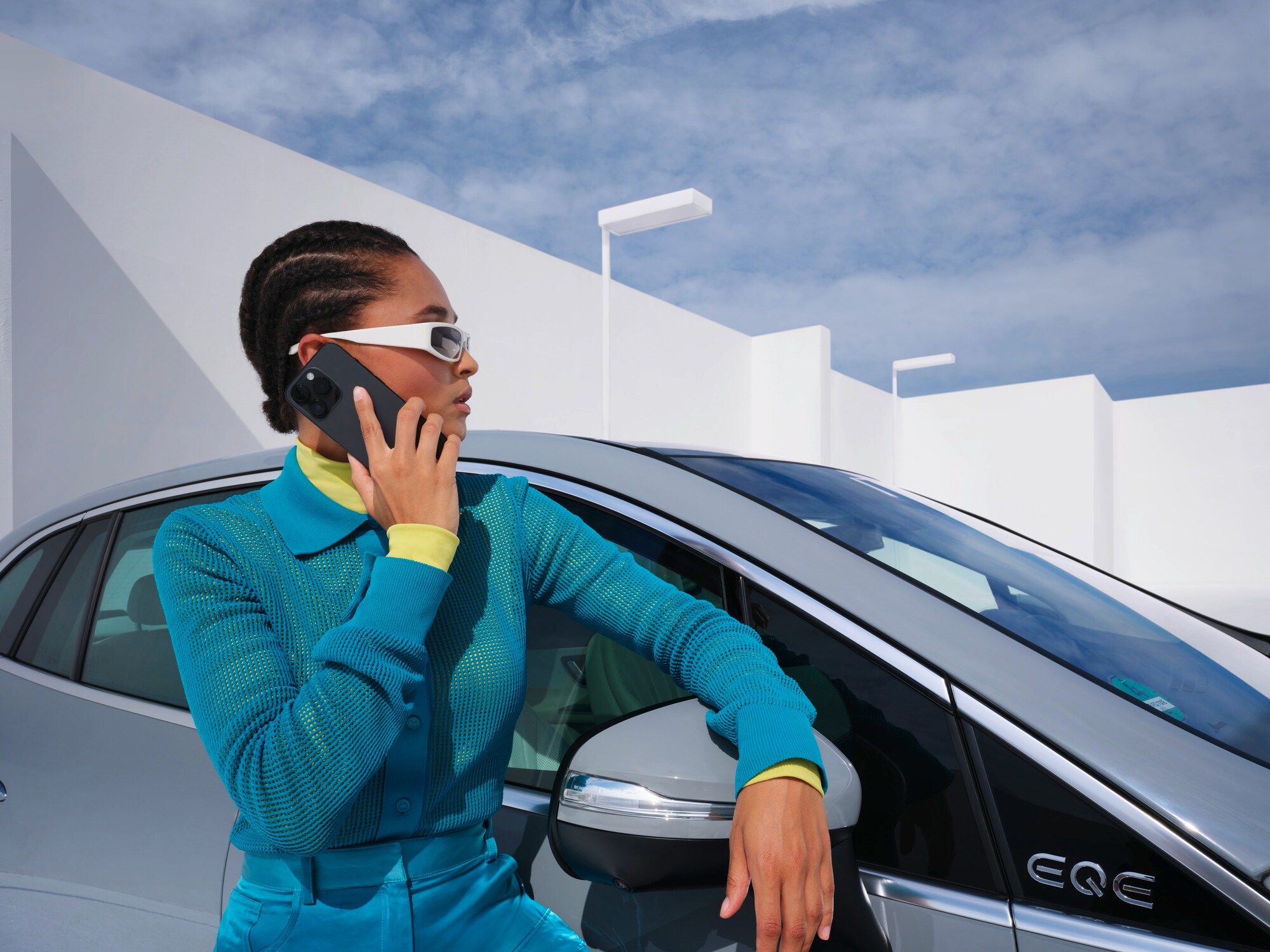 Una persona appoggiata a una vettura Mercedes-Benz con il telefono in mano.