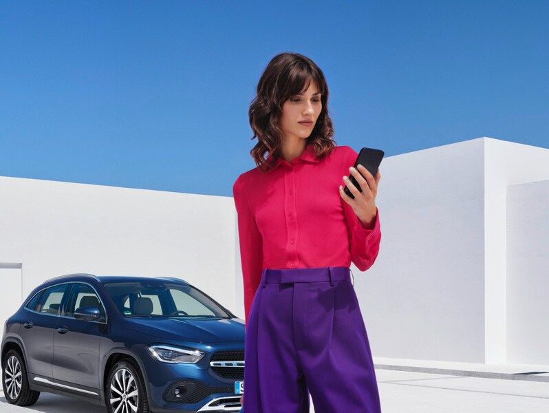 Una donna al telefono davanti alla sua Mercedes