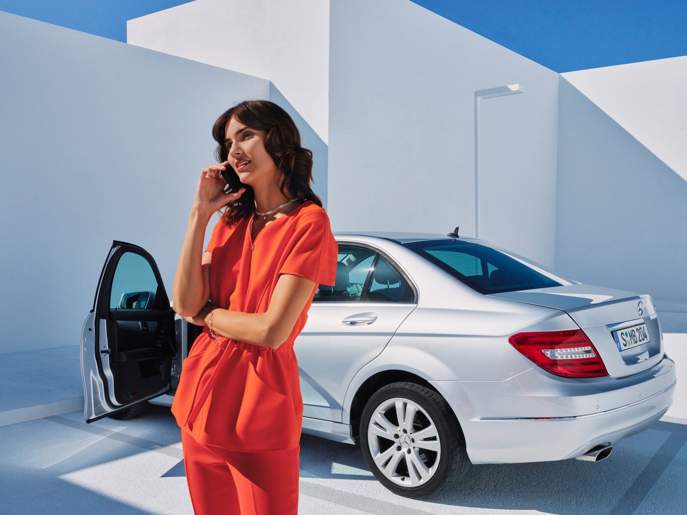 Una donna mentre parla al telefono davanti alla sua Mercedes-Benz
