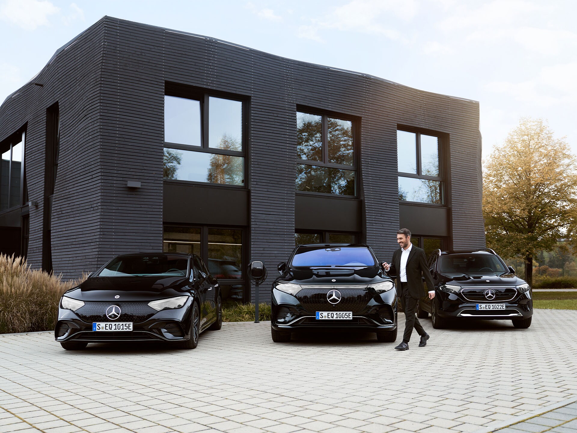 Tre auto elettriche Mercedes-Benz davanti a un edificio che ospita degli uffici.