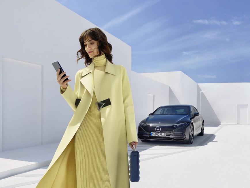 Una donna con il suo smartphone davanti a una Mercedes-Benz.