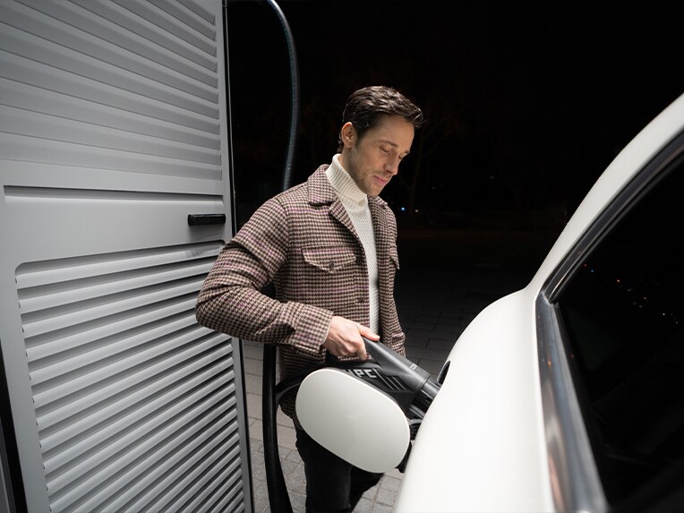 Un uomo ricarica un veicolo elettrico Mercedes-Benz presso una stazione di ricarica.