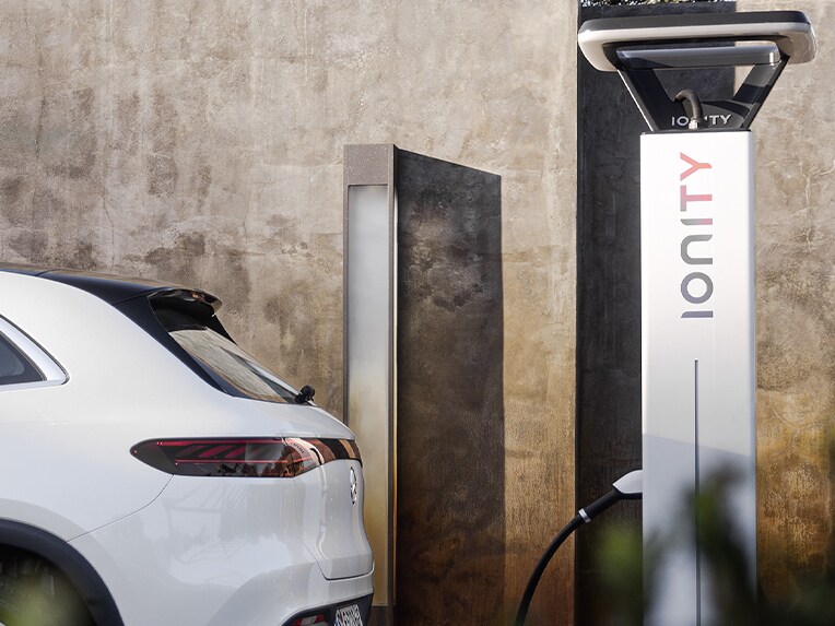 Un uomo ricarica la sua Mercedes-Benz elettrica presso una stazione di ricarica IONITY.