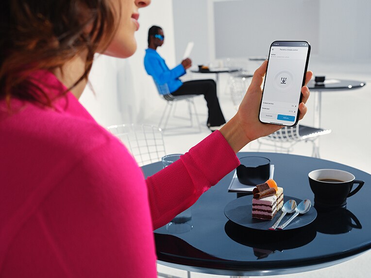 Una donna tiene in mano lo smartphone e utilizza l'app Mercedes me.
