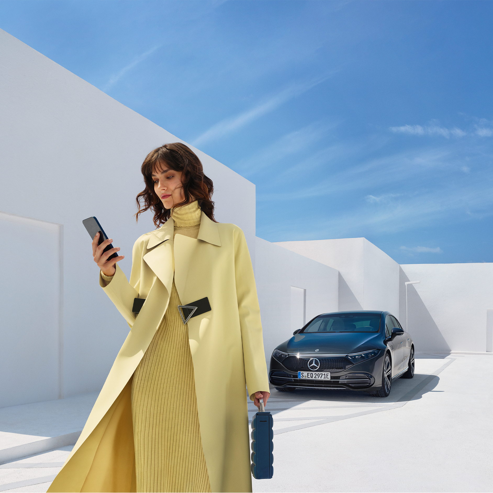 Acquista Digital Extras | Entertainment | Mercedes-Benz Una donna guarda il suo cellulare mentre si allontana dalla sua vettura elettrica