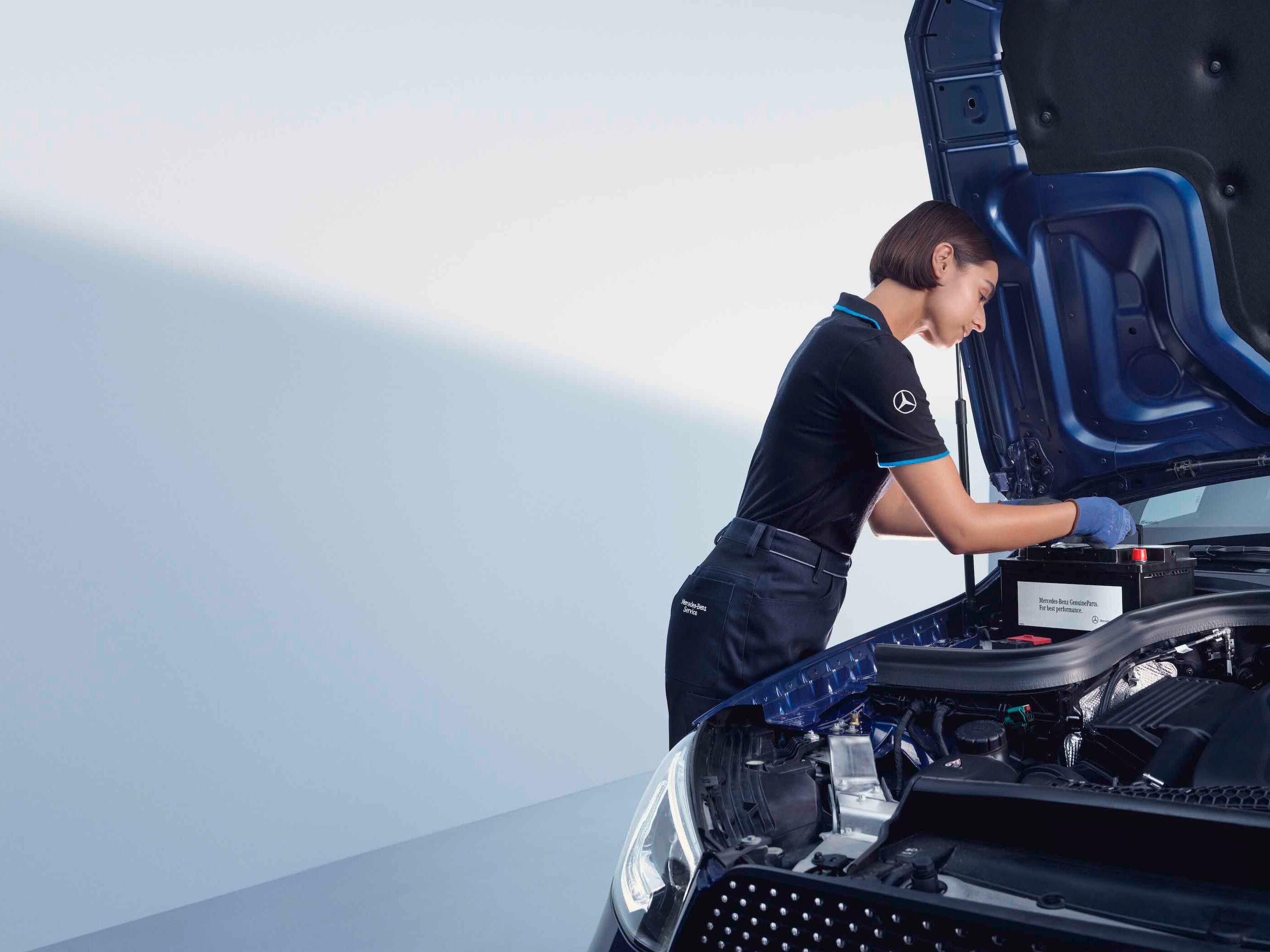 Un meccanico si china sul cofano aperto di una Mercedes-Benz.