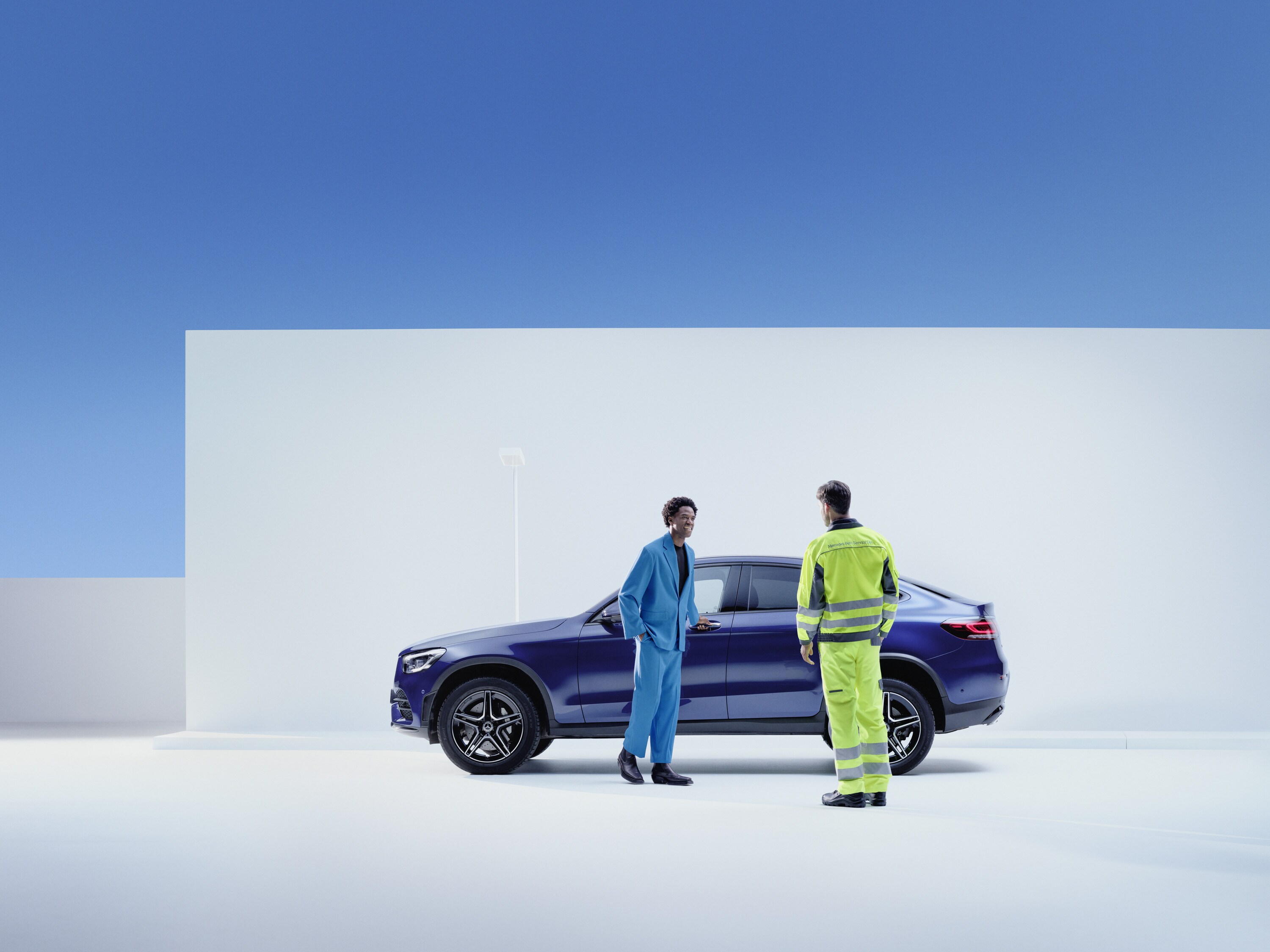 Un addetto all'assistenza Mercedes-Benz si trova accanto a un cliente sulla fiancata della sua Mercedes-Benz.