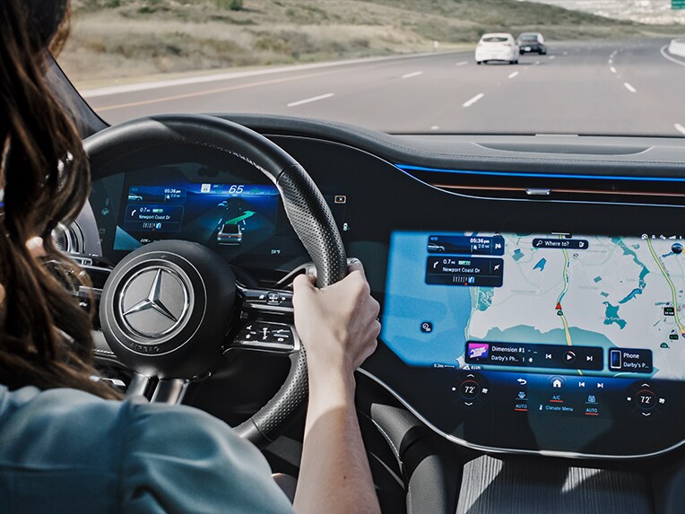 Mentre guida in autostrada, una persona segue il sistema di navigazione MBUX Mercedes-Benz che la conduce verso un parcheggio libero.