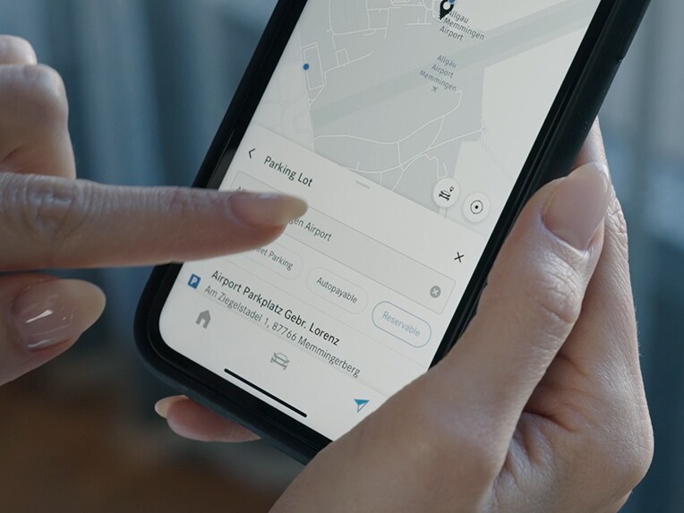 Una persona tocca il proprio smartphone e con Off-Street Parking visualizza i prezzi del parcheggio libero.