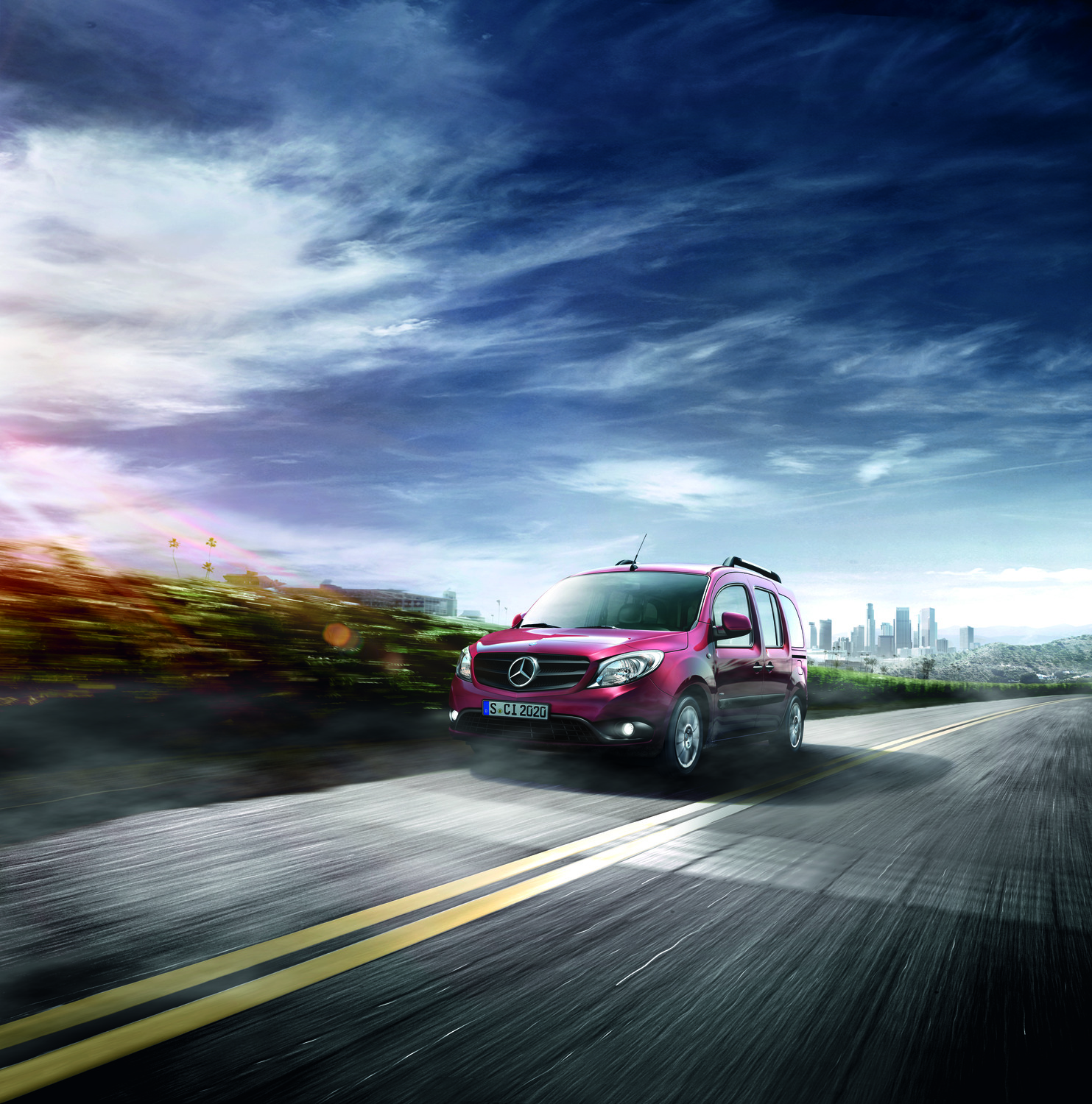 Scopri il dinamico Mercedes-Benz Citan Un Mercedes-Benz Citan rosso mentre percorre una strada panoramica con lo skyline della città sullo sfondo