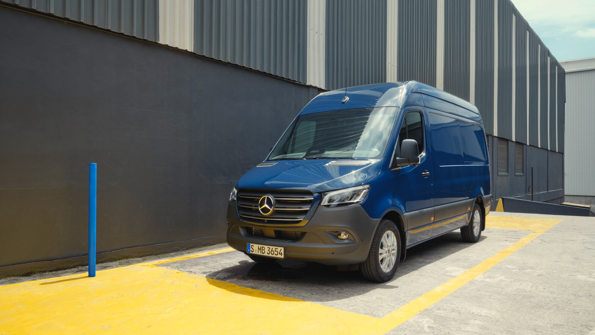 Un veicolo commerciale Mercedes-Benz Sprinter blu parcheggiato presso un edificio industriale