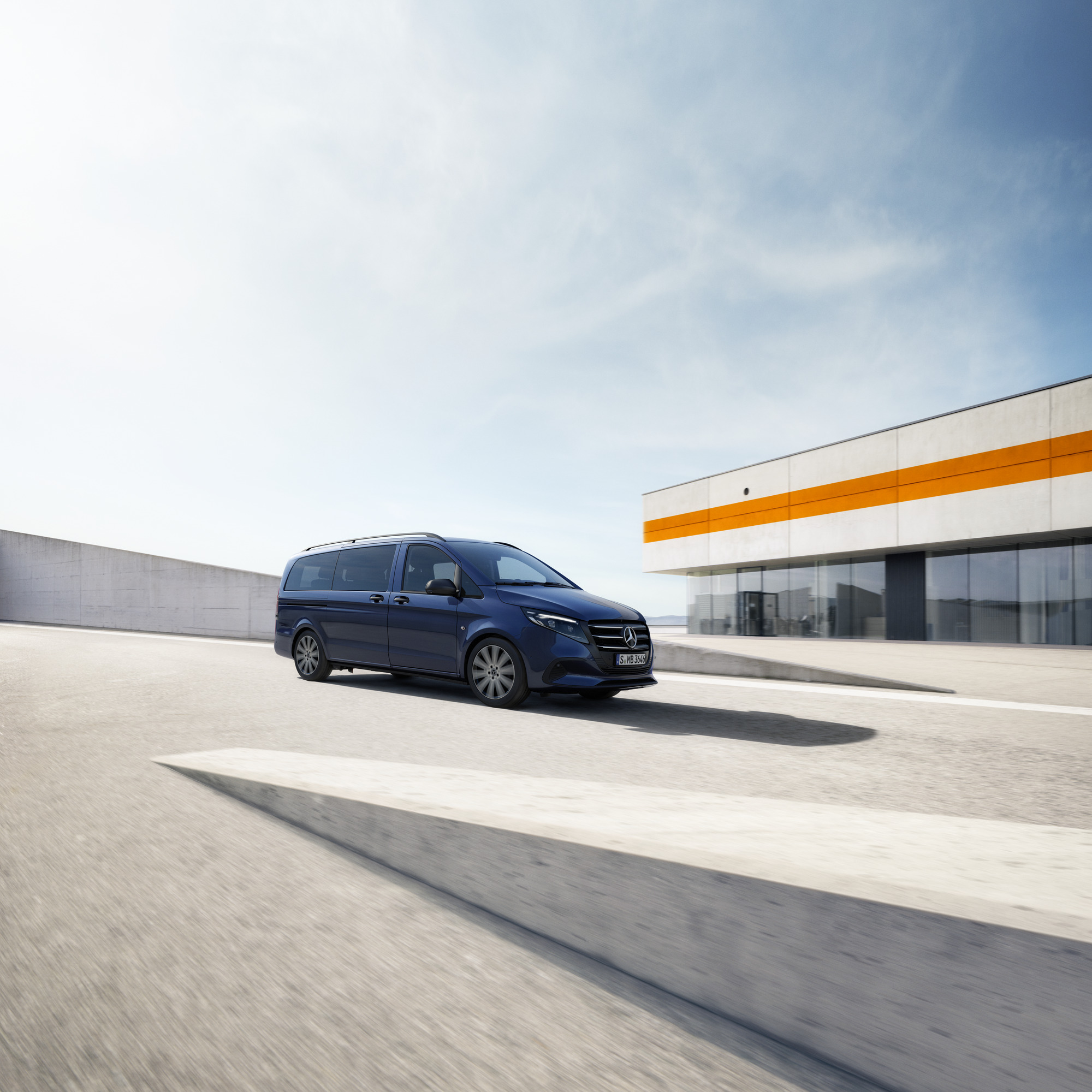 Un elegante veicolo commerciale Mercedes-Benz Classe V In veicolo commerciale Mercedes-Benz Classe V mentre passa davanti a un edificio moderno