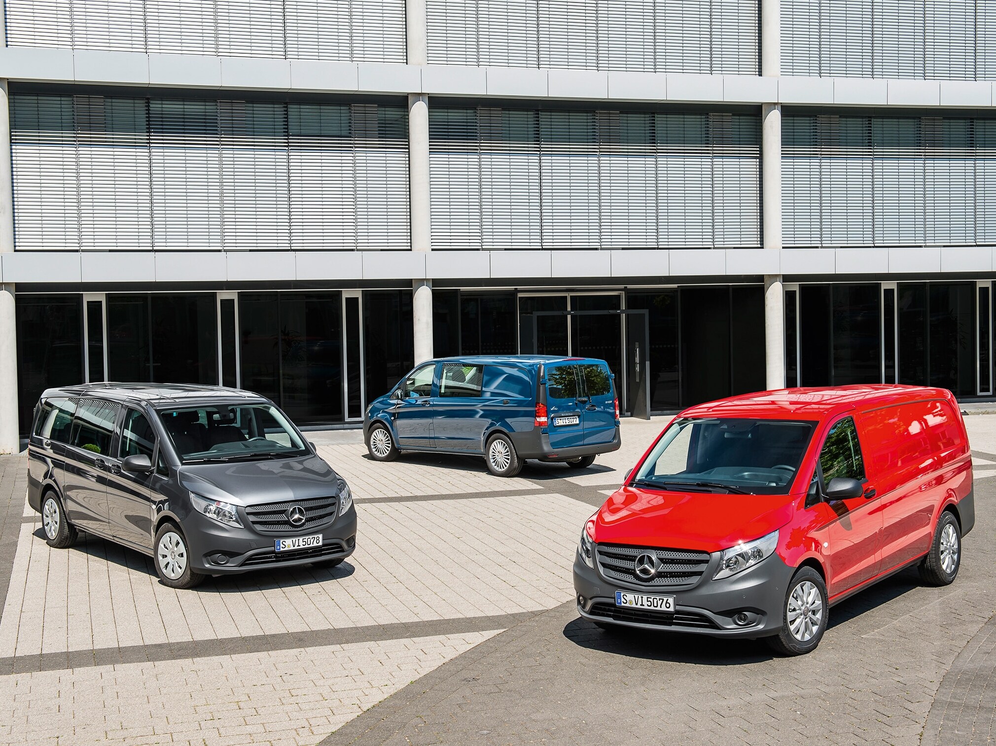 Diversi Mercedes-Benz Vito parcheggiati davanti a un moderno edificio adibito a uffici