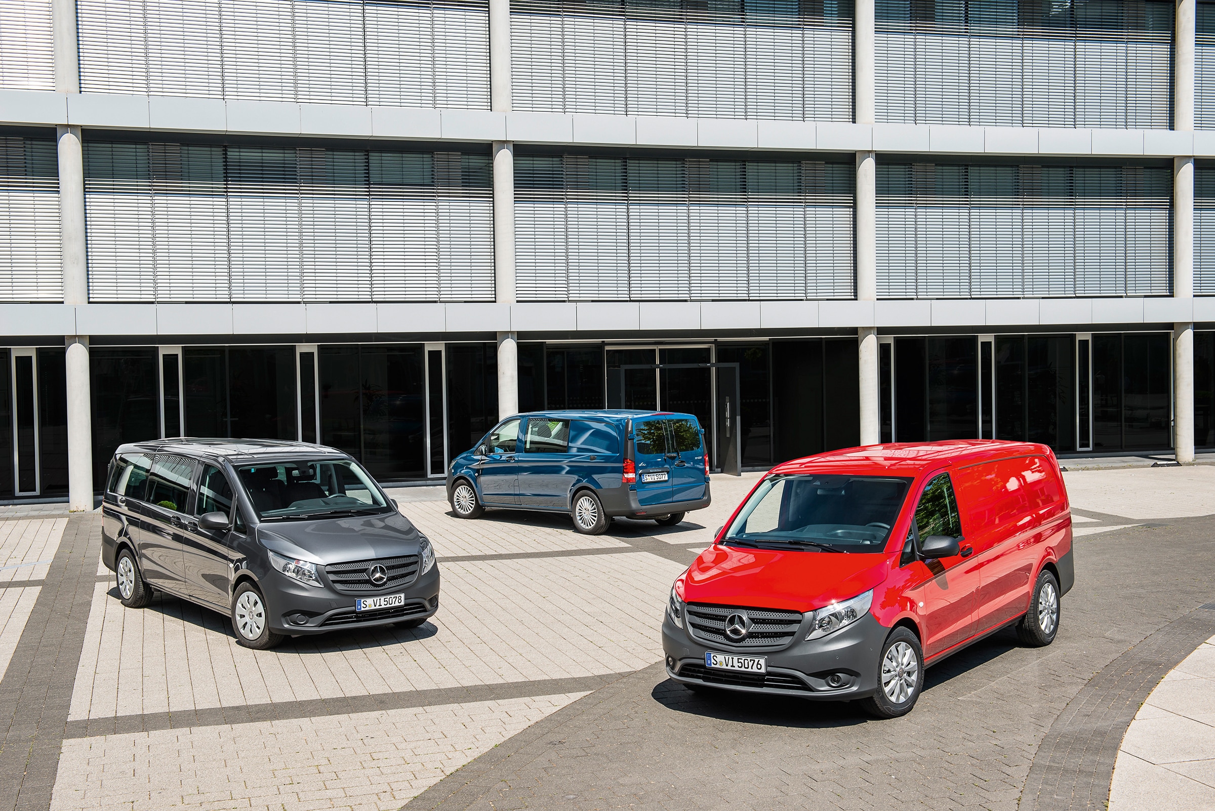 La terza generazione dei Mercedes-Benz Vito | Storia dei veicoli commerciali | Mercedes-Benz Diversi Mercedes-Benz Vito parcheggiati davanti a un moderno edificio adibito a uffici