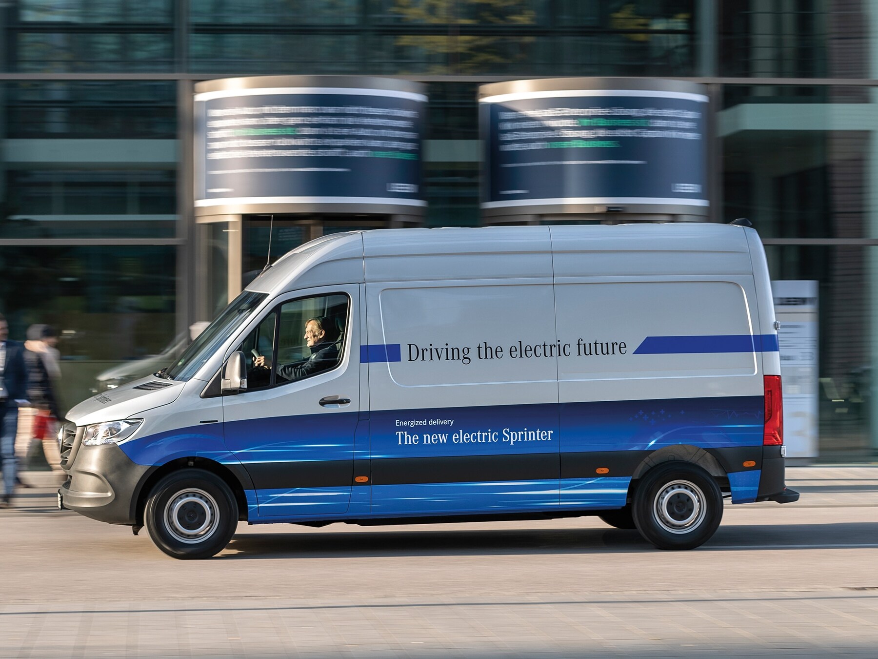Un furgone Mercedes-Benz eSprinter Panel Van mentre percorre una strada di una città moderna