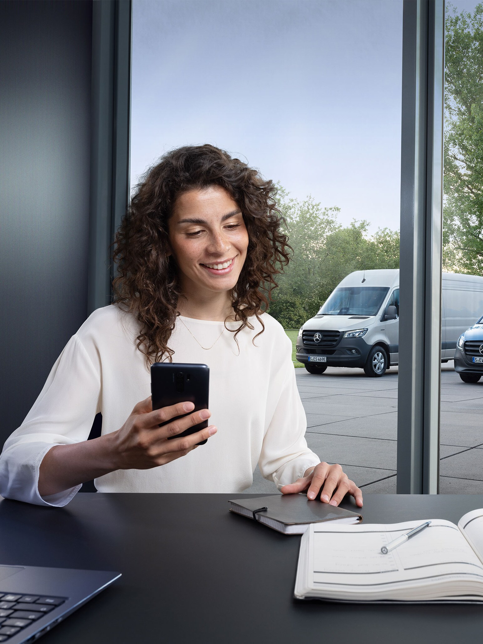 Una donna con uno smartphone seduta alla scrivania