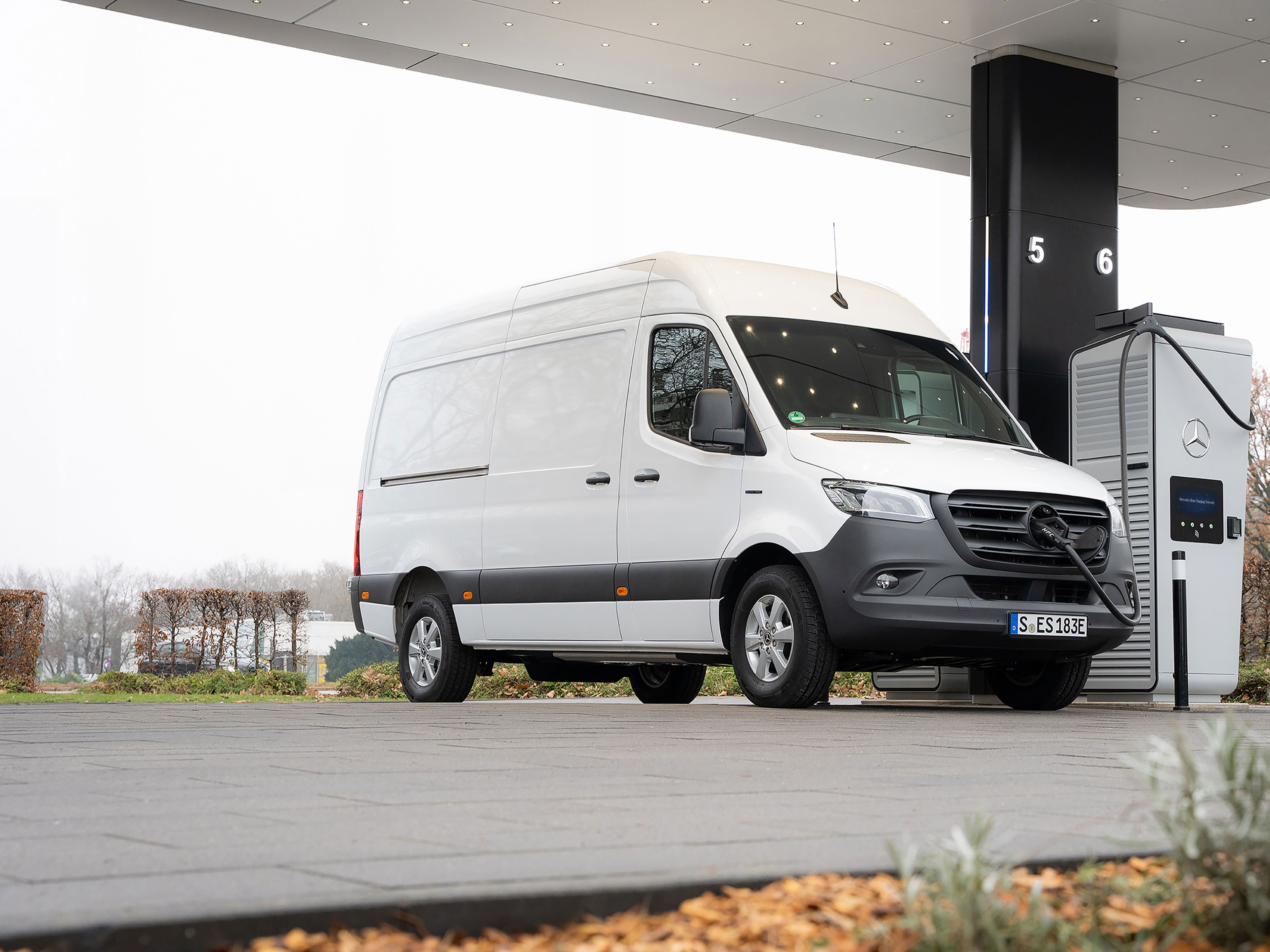 Rete di ricarica Mercedes-Benz | Ricarica in viaggio | Veicoli commerciali Mercedes-Benz Un veicolo commerciale Mercedes-Benz davanti a una stazione di ricarica durante la ricarica.