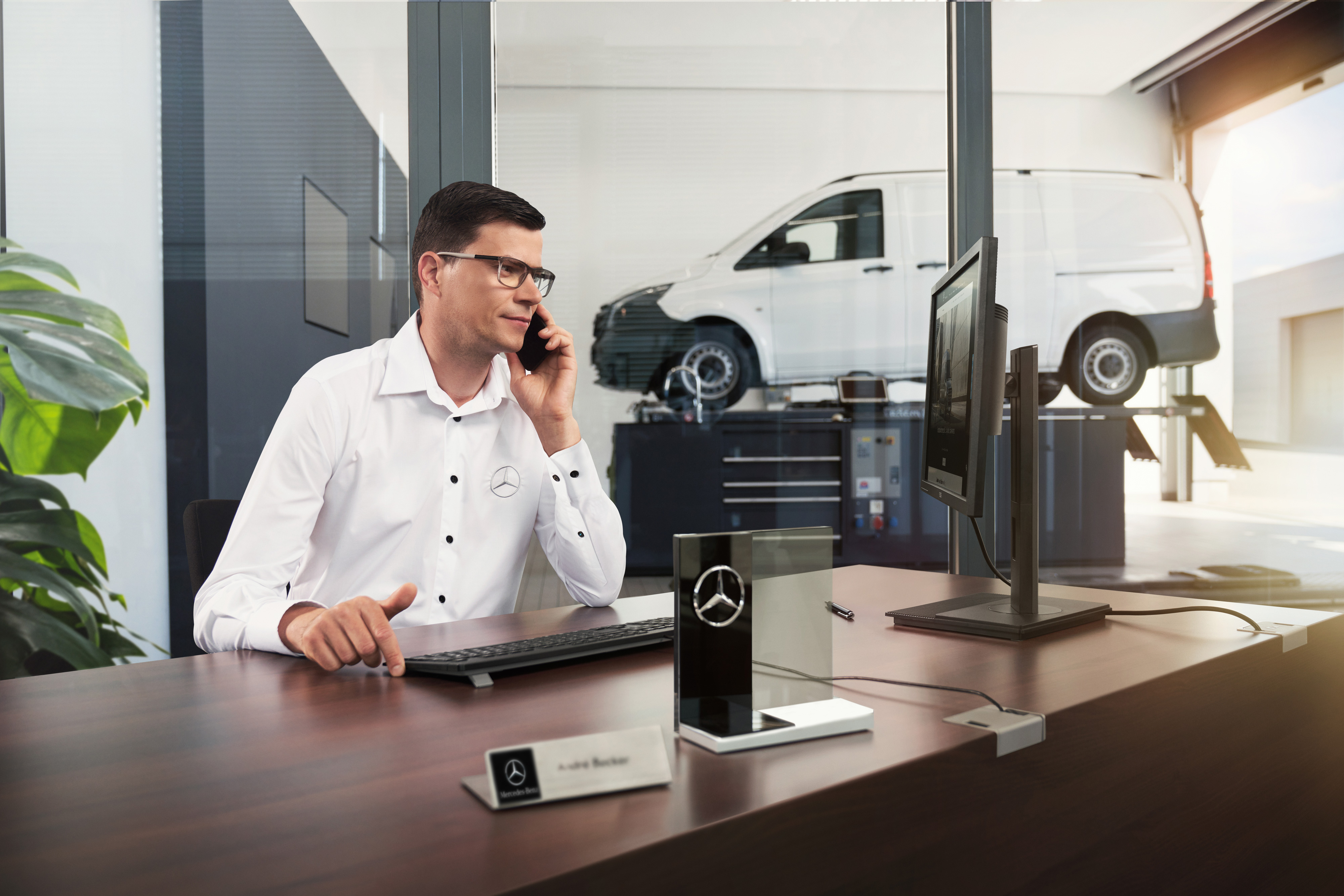 Mercedes-Benz | Convenience | Partner di assistenza Un consulente del servizio assistenza Mercedes-Benz mentre parla al telefono in un'officina.