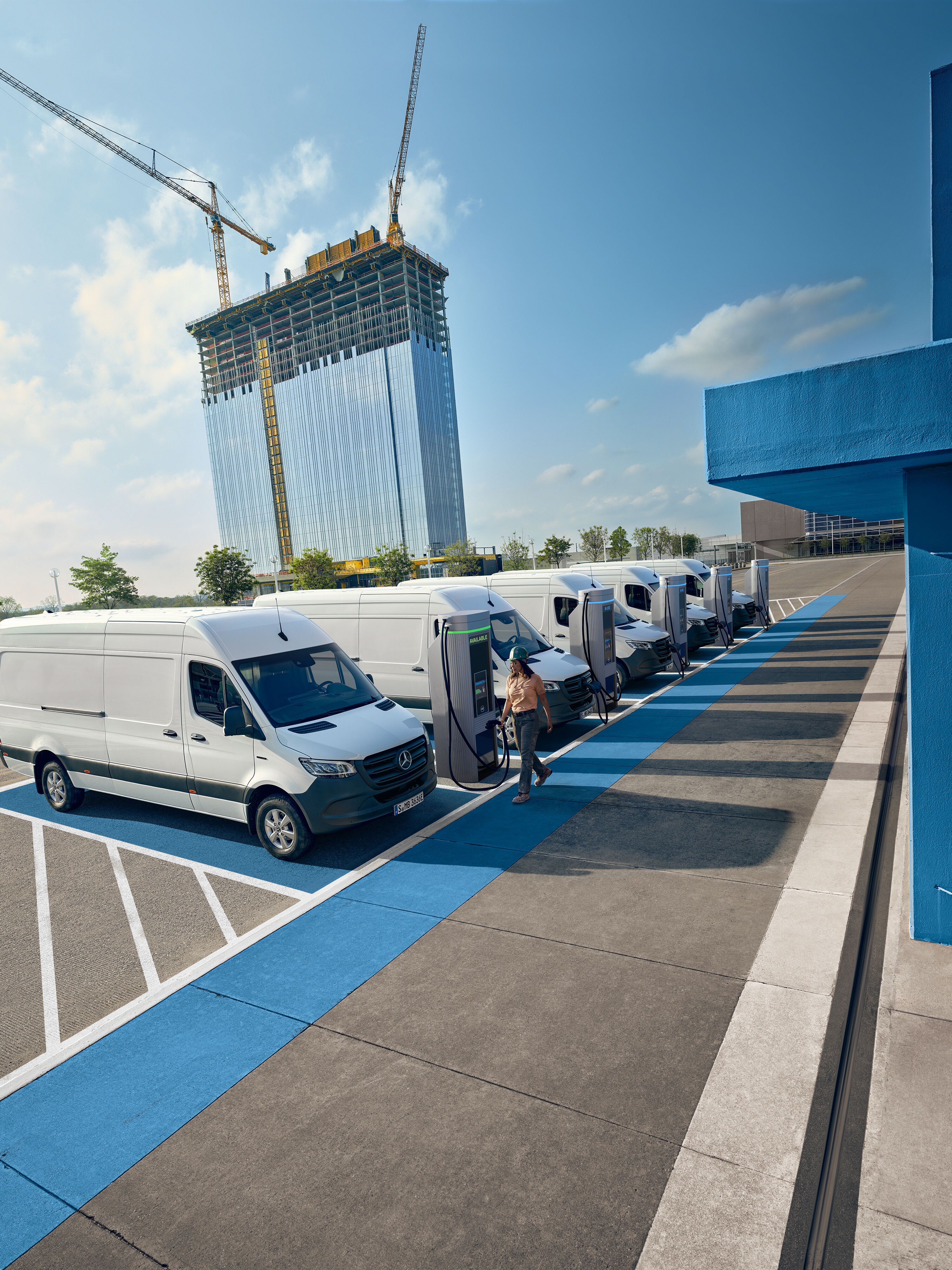 Una flotta di veicoli commerciali elettrici bianchi Mercedes-Benz parcheggiati presso una stazione di ricarica.