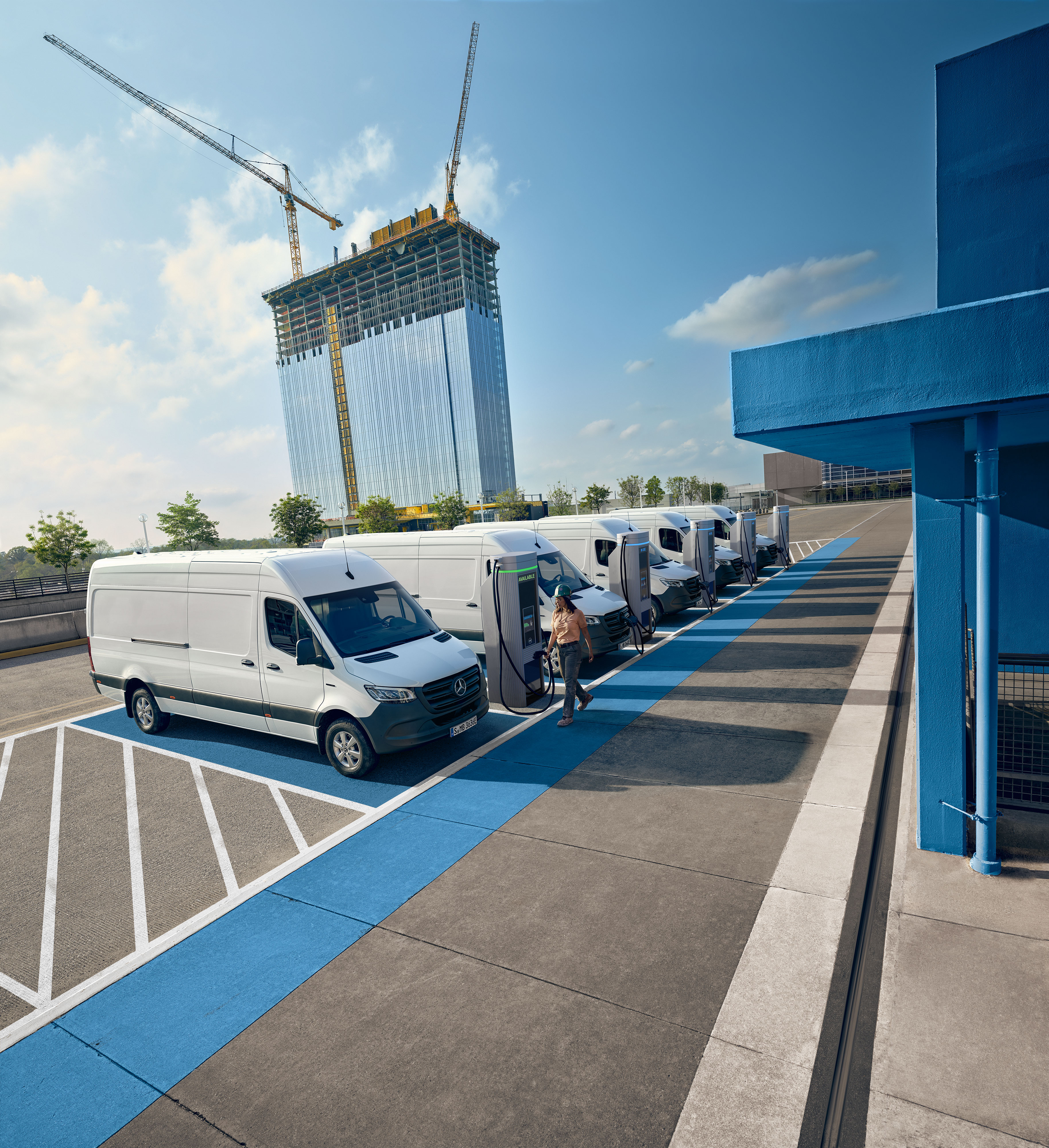 Mercedes-Benz | Convenience Una flotta di veicoli commerciali elettrici bianchi Mercedes-Benz parcheggiati presso una stazione di ricarica.
