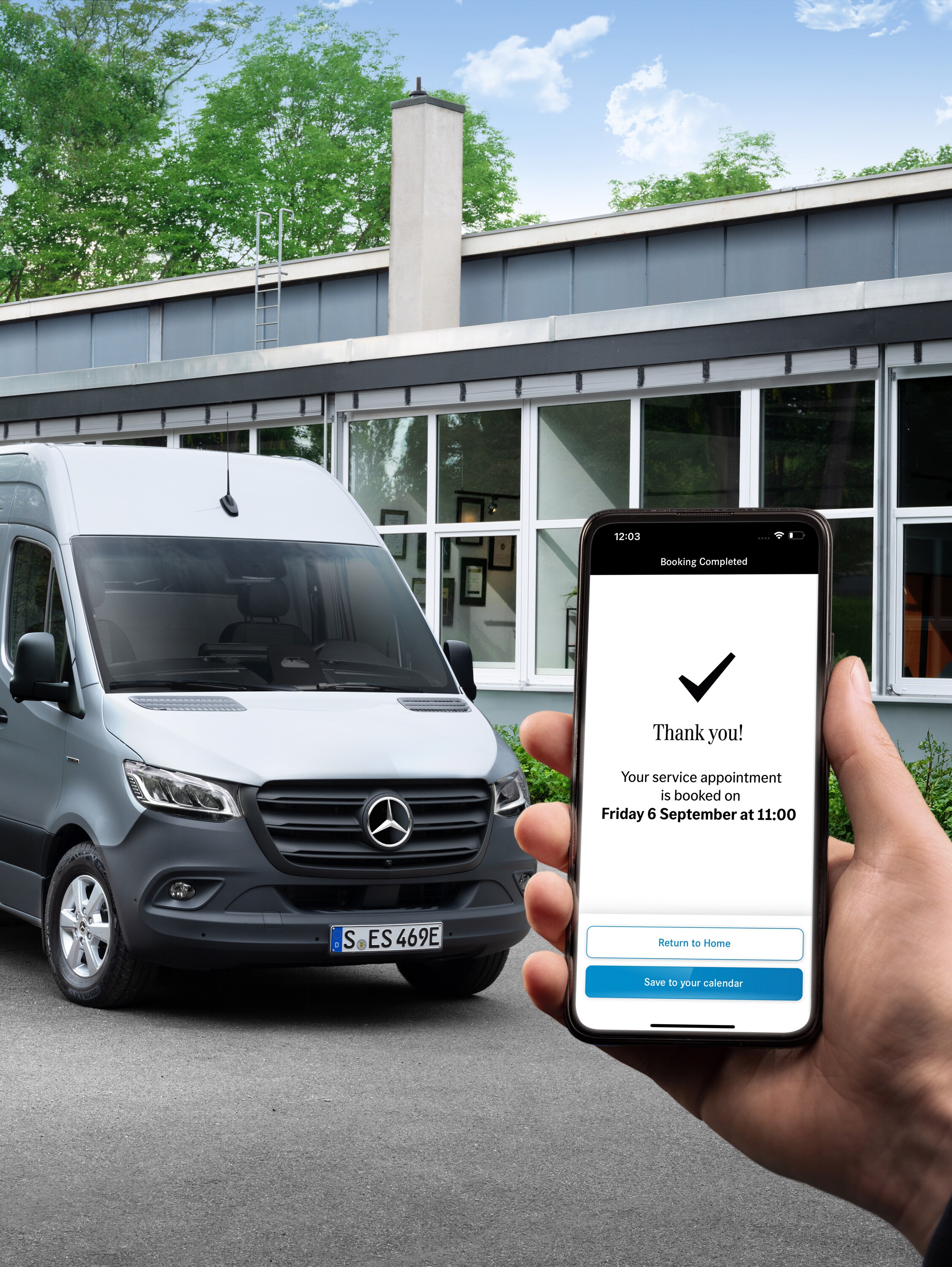 Un veicolo commerciale Mercedes-Benz Sprinter grigio davanti a un ufficio, accanto una persona in primo piano che tiene in mano uno smartphone.