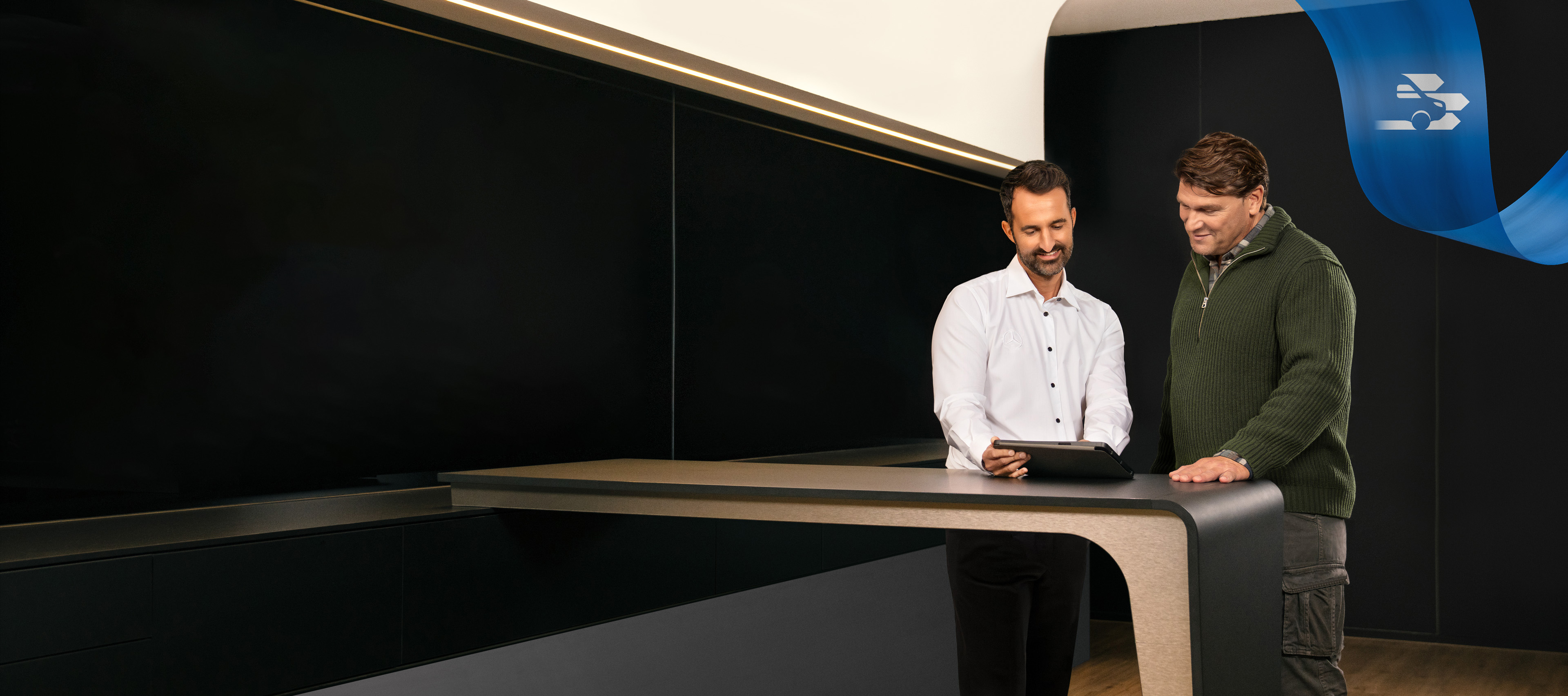 Mercedes-Benz | Convenience | Mercedes-Benz Service Due uomini in piedi nell'ufficio di un Mercedes-Benz Service mentre discutono di qualcosa visto su un tablet