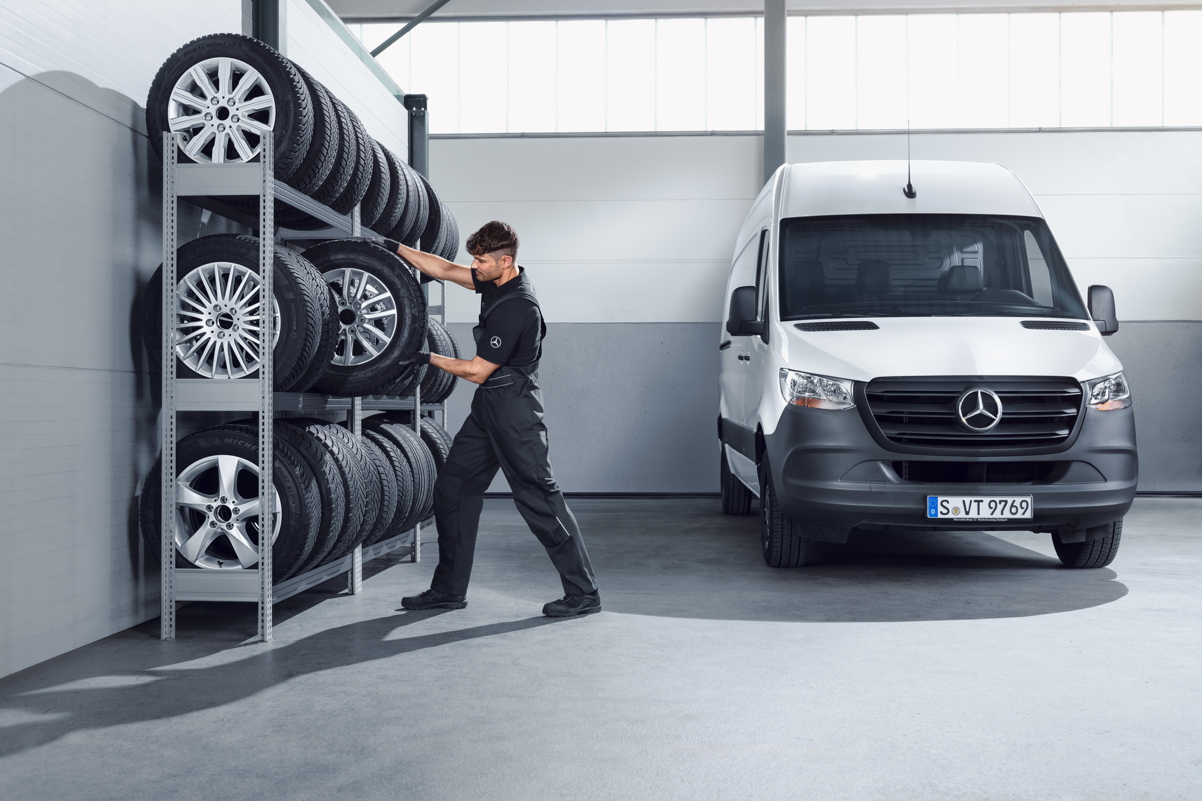 Mercedes-Benz | Ricambi originali di qualità per i veicoli commerciali Un meccanico sceglie dallo scaffale dell'officina le ruote invernali complete Mercedes-Benz per uno Sprinter bianco.