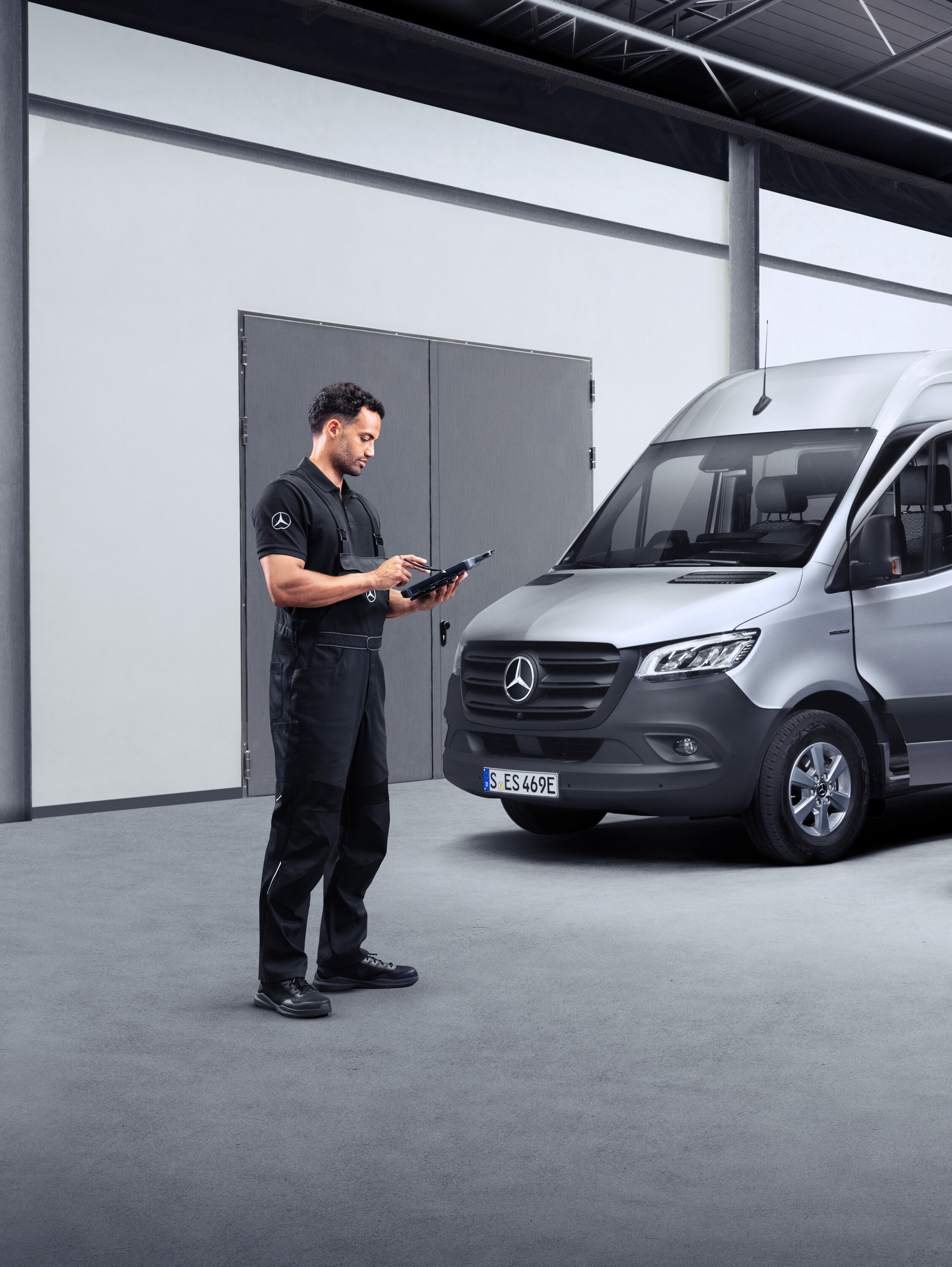 Un tecnico davanti a due veicoli commerciali elettrici visualizzati su un tablet