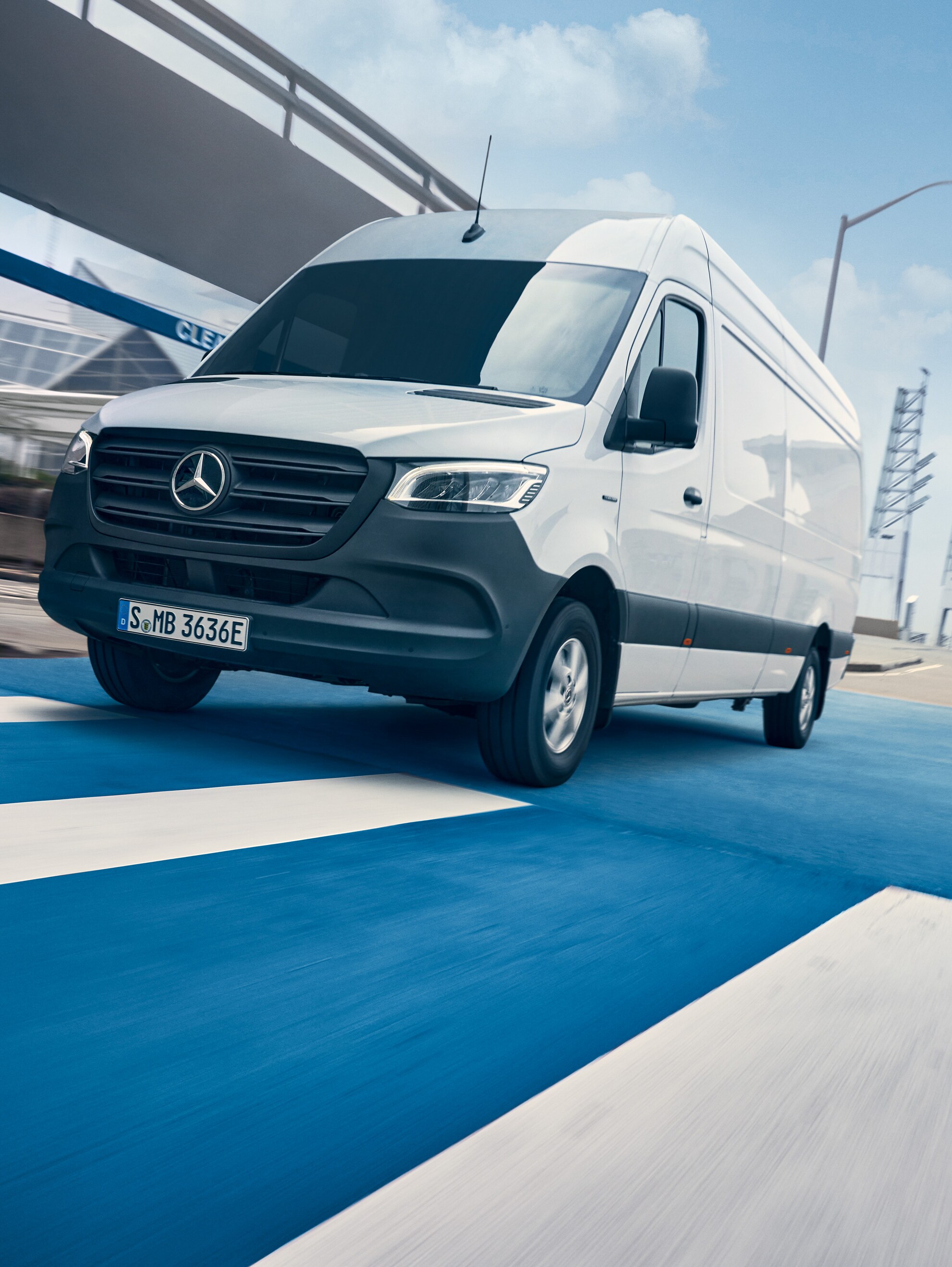 Un Mercedes-Benz Sprinter bianco percorre una strada in città.