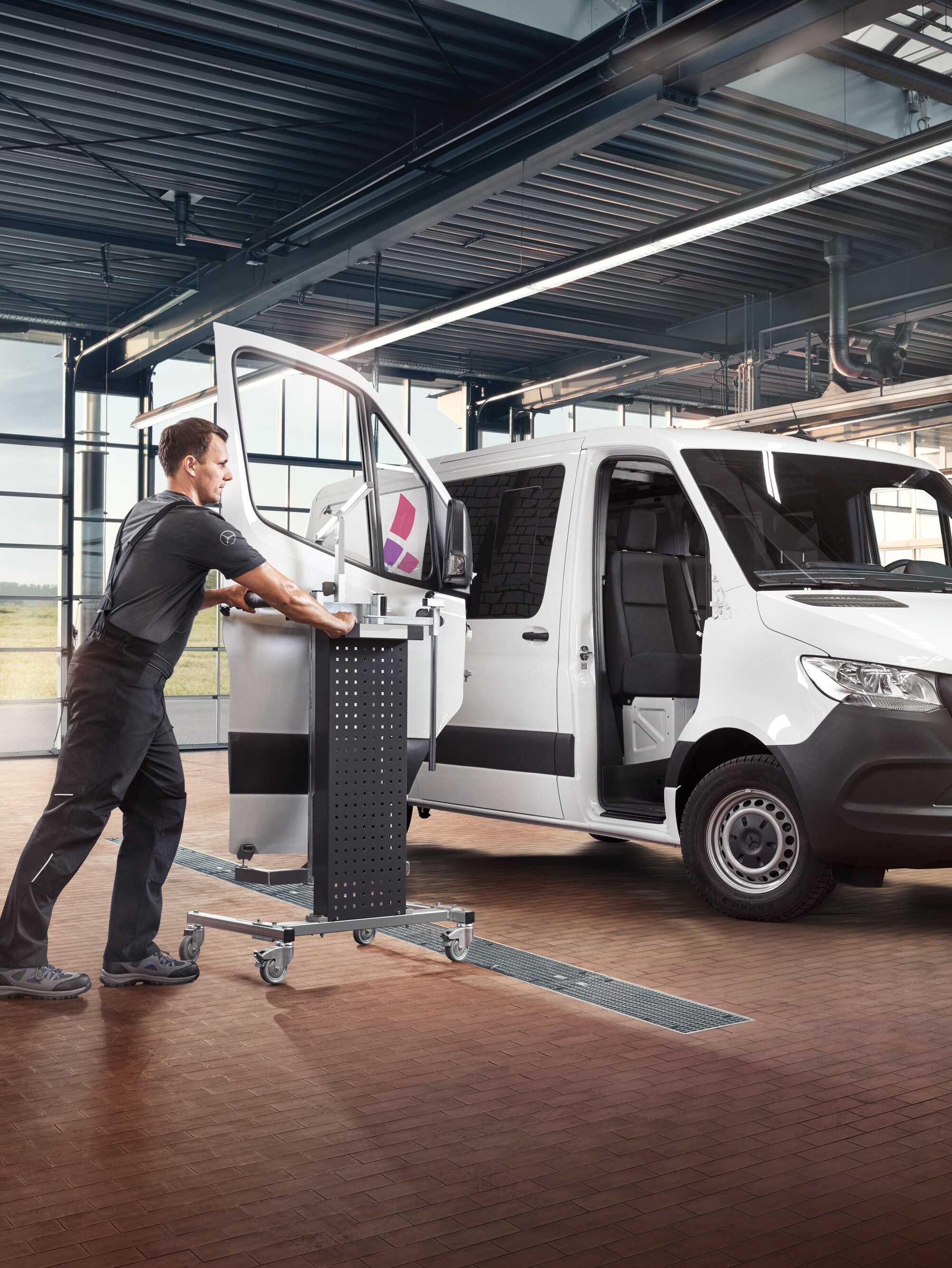 Un tecnico esegue la manutenzione della porta del passeggero di un veicolo commerciale Mercedes-Benz Sprinter bianco.
