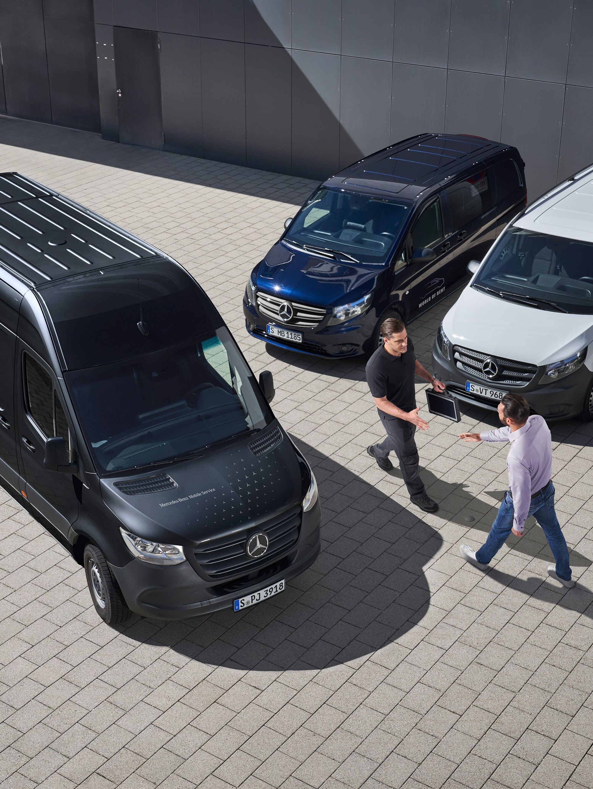 Due uomini si salutano tra alcuni veicoli commerciali Mercedes-Benz.