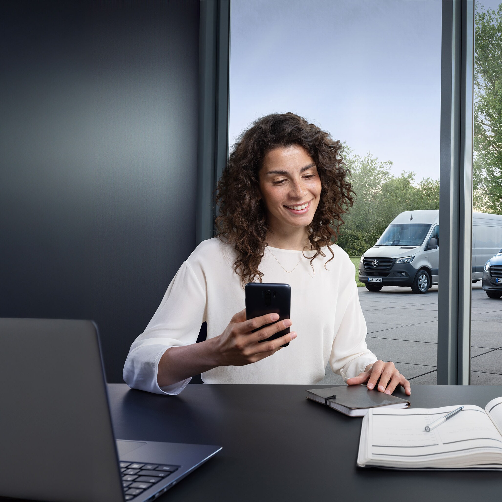 Cliente al telefono davanti a una serie di furgoni Mercedes-Benz.
