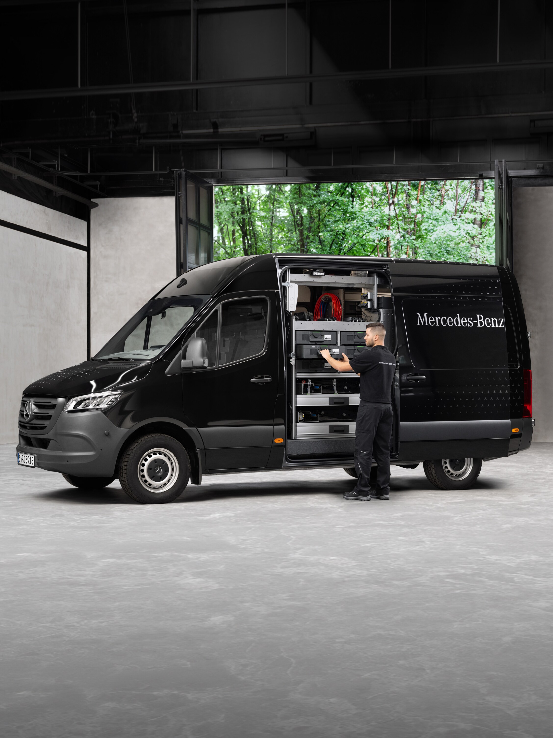 Un tecnico rimuove gli attrezzi da un veicolo commerciale Mercedes-Benz Sprinter nero.