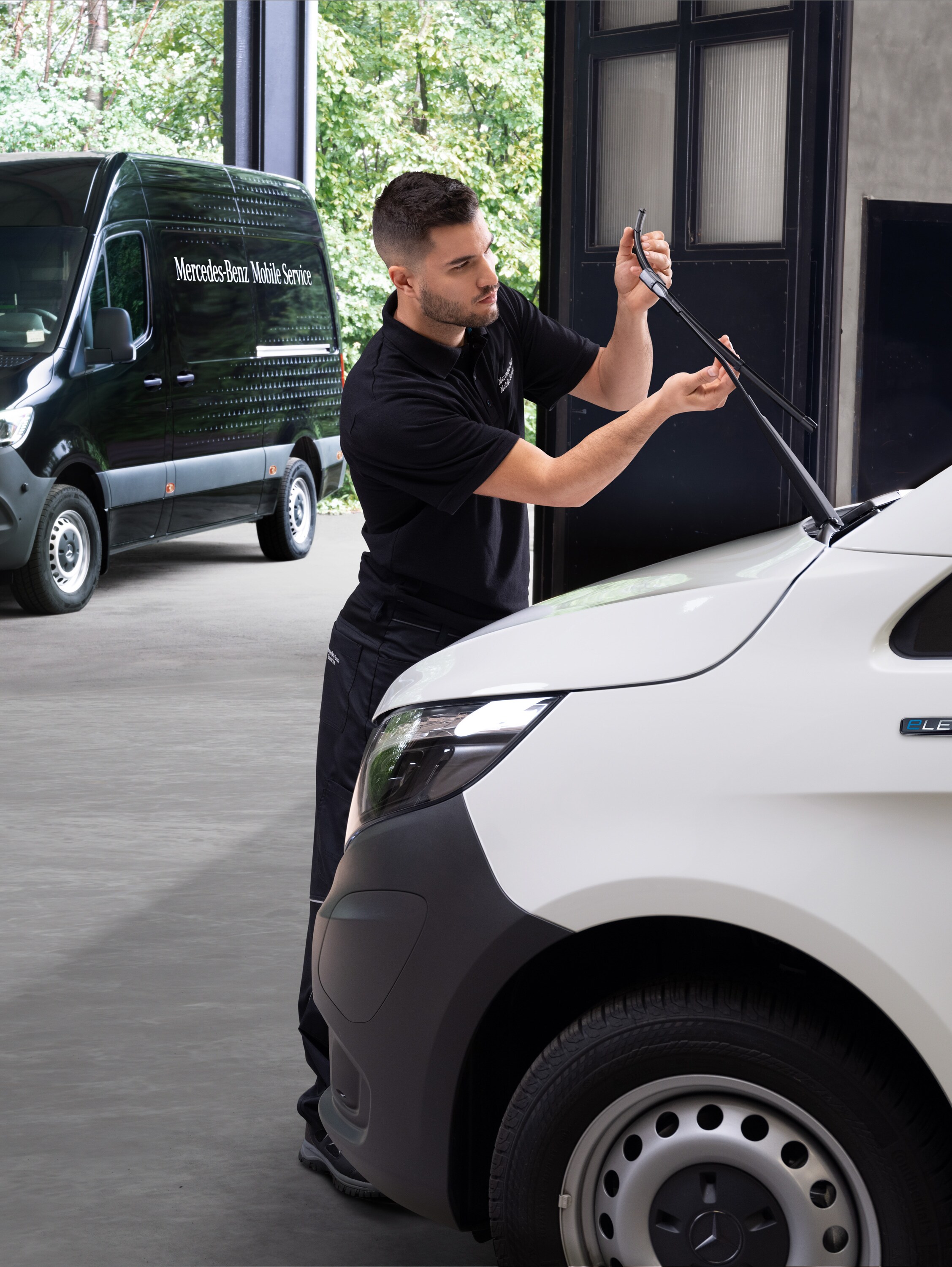 Un tecnico cambia le spazzole dei tergicristalli su un veicolo commerciale Mercedes-Benz Vito bianco.